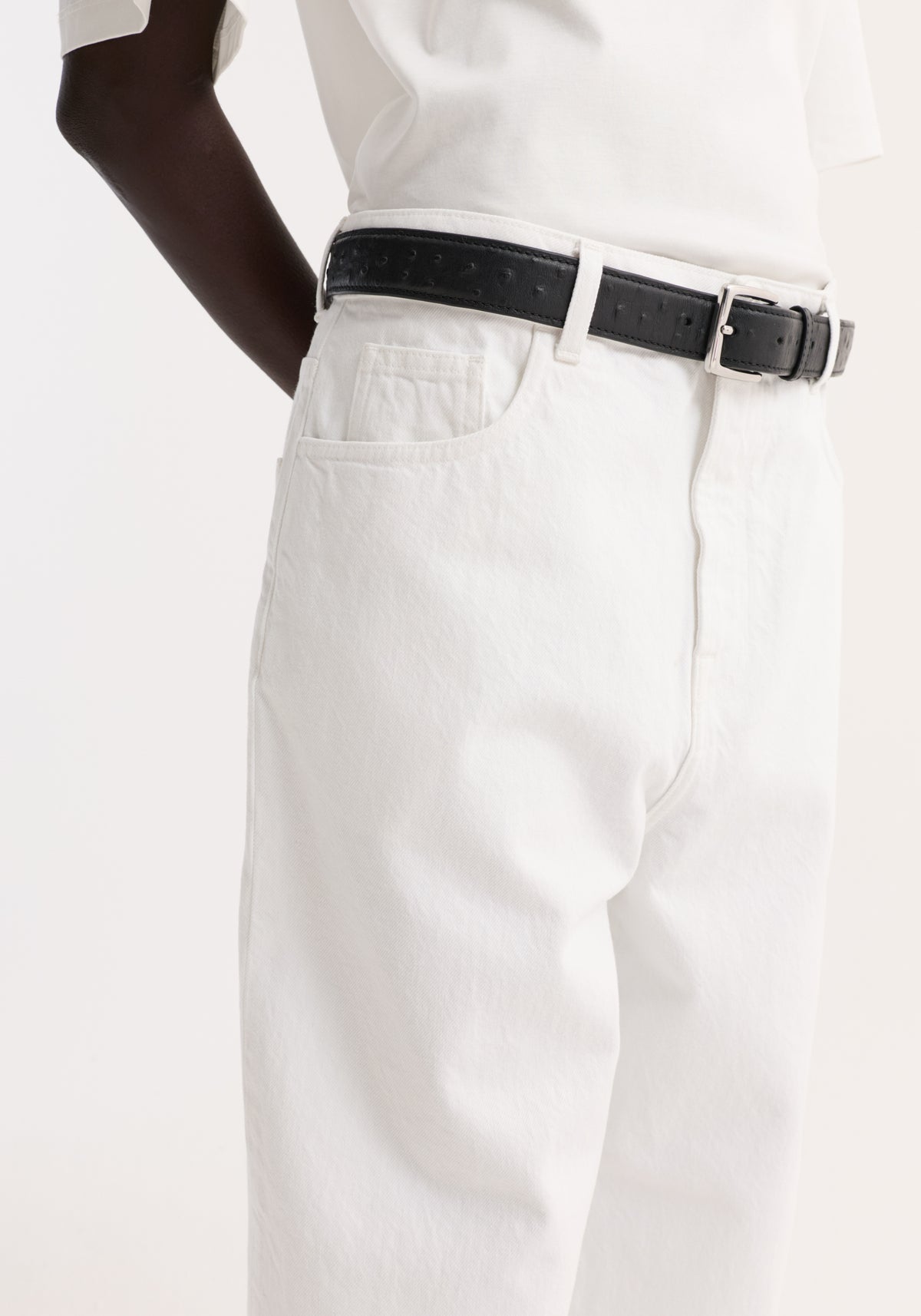 Baggy fit turn-up denim in optic white, showcasing a low-rise, baggy style with a black leather belt, highlighting the waist and wide leg design.