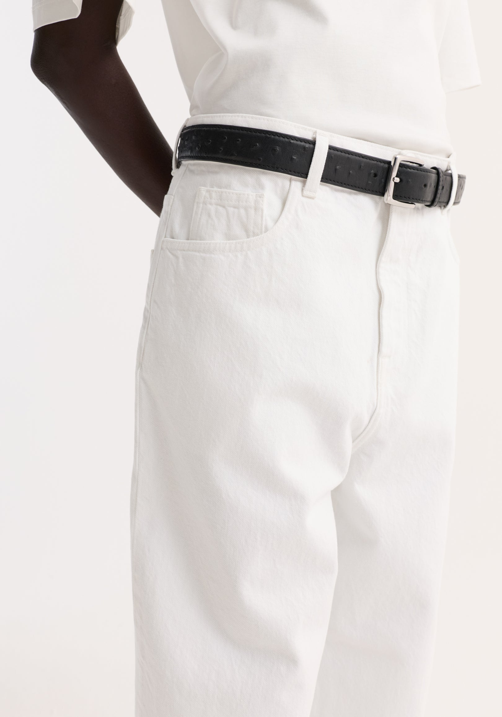 Baggy fit turn-up denim in optic white, showcasing a low-rise, baggy style with a black leather belt, highlighting the waist and wide leg design.