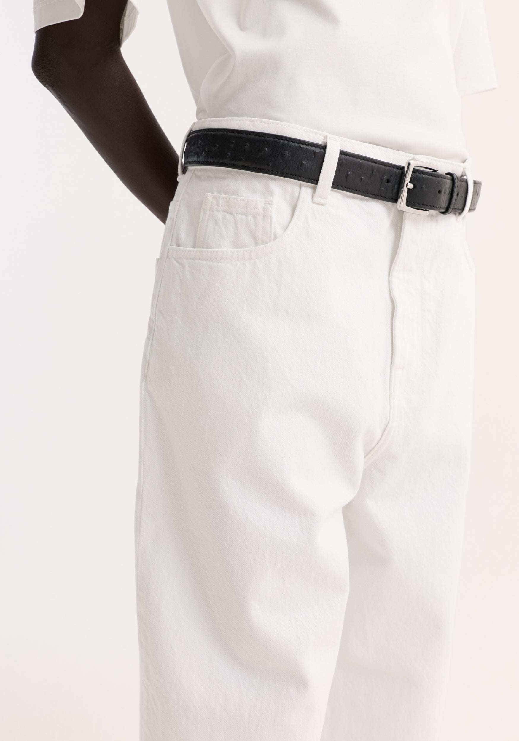 Baggy fit turn-up denim in optic white, showcasing a low-rise, baggy style with a black leather belt, highlighting the waist and wide leg design.