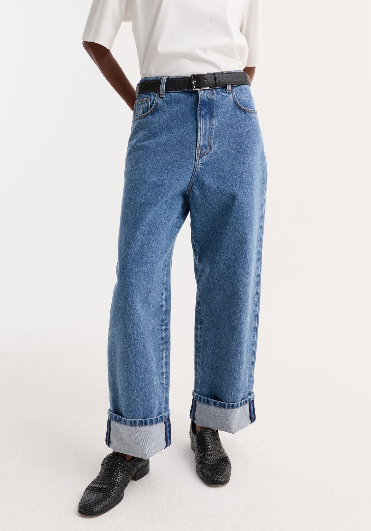 Turn-up baggy denim in heritage blue with wide, rolled-up cuffs and a low-waist fit, styled with a tucked-in white T-shirt and black loafers.