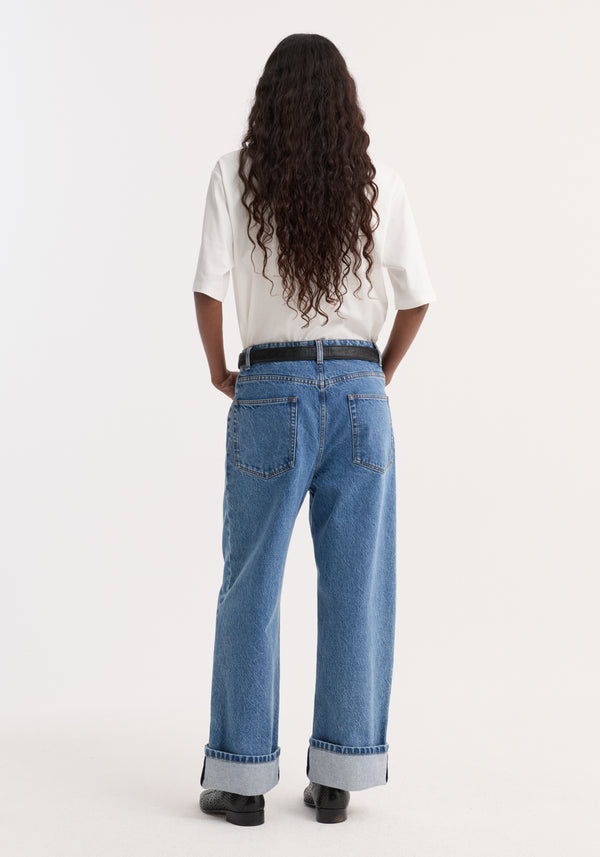 Turn-up baggy denim | heritage blue shown on person with long hair, featuring a low-rise fit, straight legs, turned-up cuffs, and a black belt.