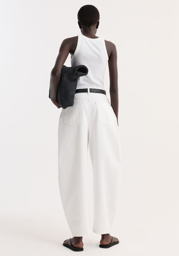 Back view of person wearing Sculptural denim trousers | optic white, featuring a high waist and balloon leg, paired with a white tank and black belt.