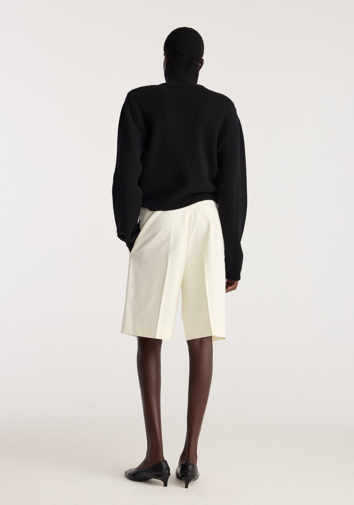 Tailored single pleat shorts | off white shown from the back on a model styled with a black sweater and black shoes in a studio setting
