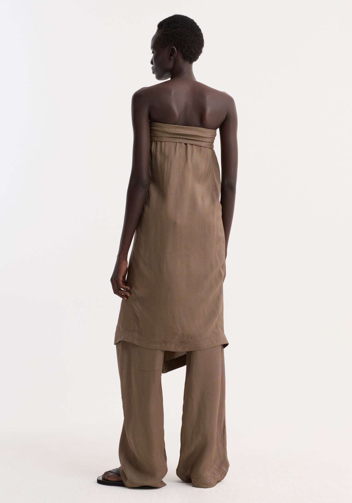 Back view of a model wearing the Sarong top with a front knot and slit, layered over matching wide-leg trousers and black sandals.