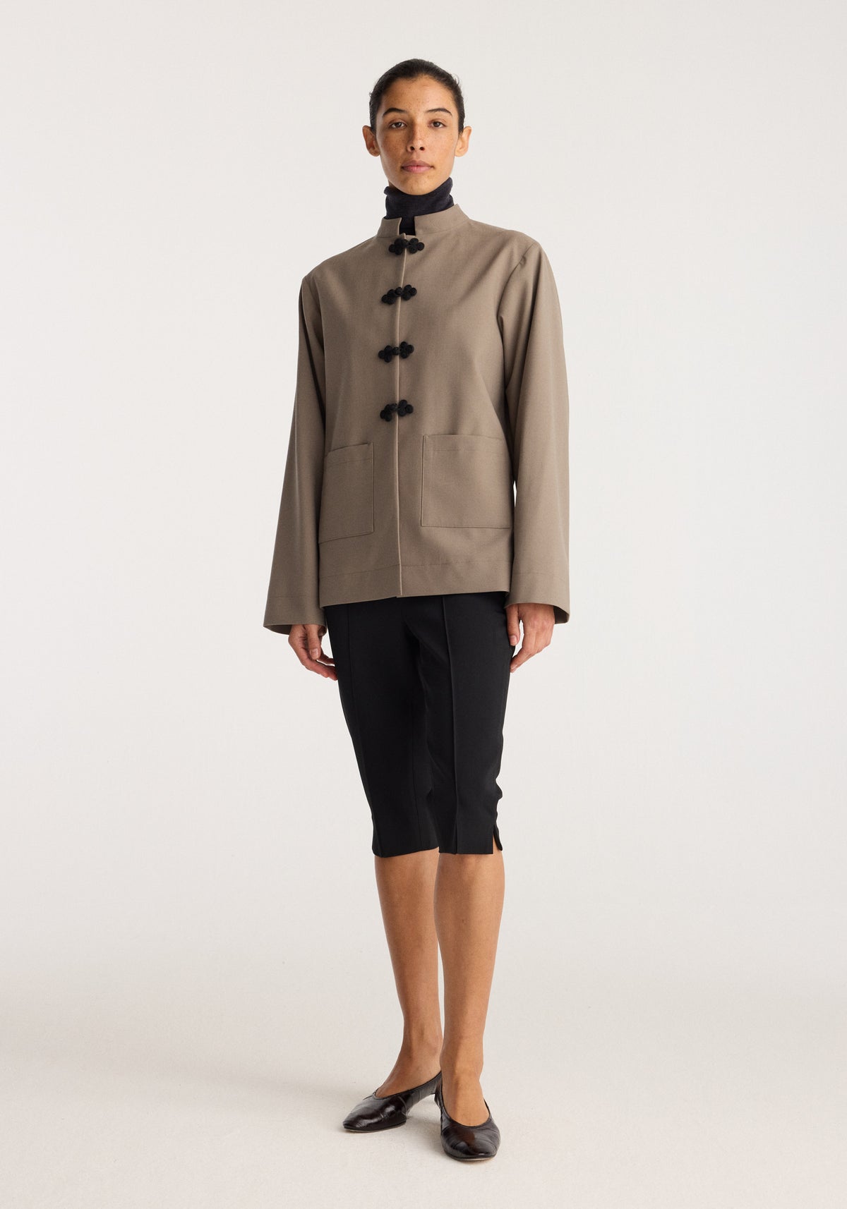 Capri | black capri trousers worn with a tailored taupe jacket and black flats, shown on a model against a neutral studio background