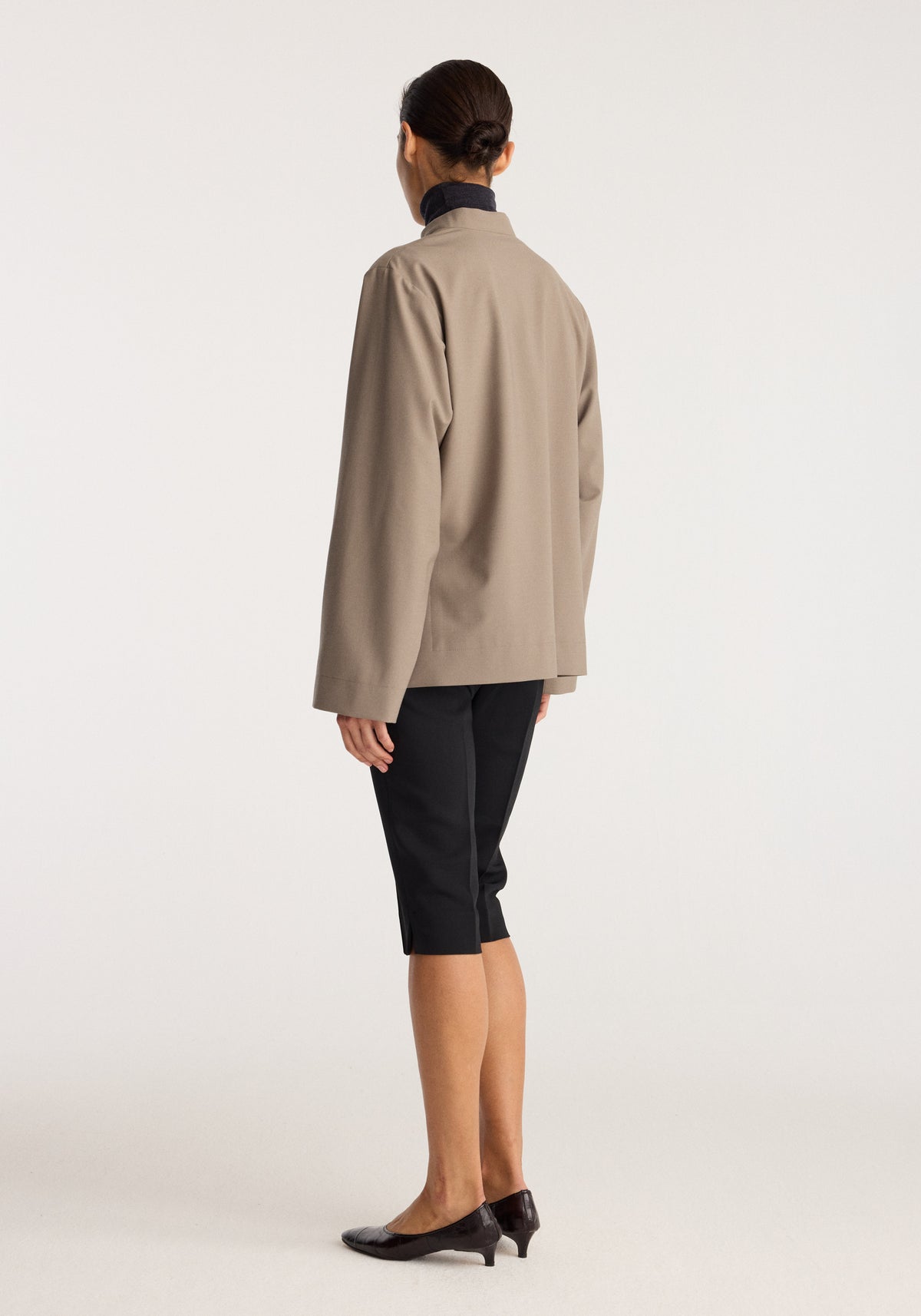 Capri | black shown from the back on a model wearing a taupe jacket with black cropped trousers and black heeled shoes
