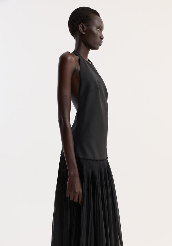 Pleated muslin halter dress | black, worn by a tall model, features a structured bodice and flowing pleated skirt, showcasing minimalist, elegant design.