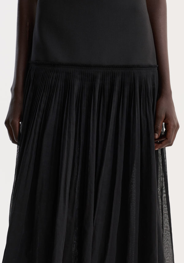 Pleated muslin halter dress | black featuring a structured bodice and finely pleated skirt, worn by a model with hands at sides, showcasing fluid movement.