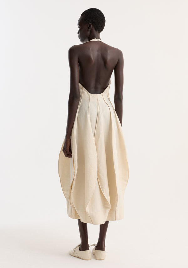 Model in Open Back Tulip Dress | Butter, showcasing a halter neckline, low back, and balloon pleats, highlighting the garment's sculptural flow and elegance.