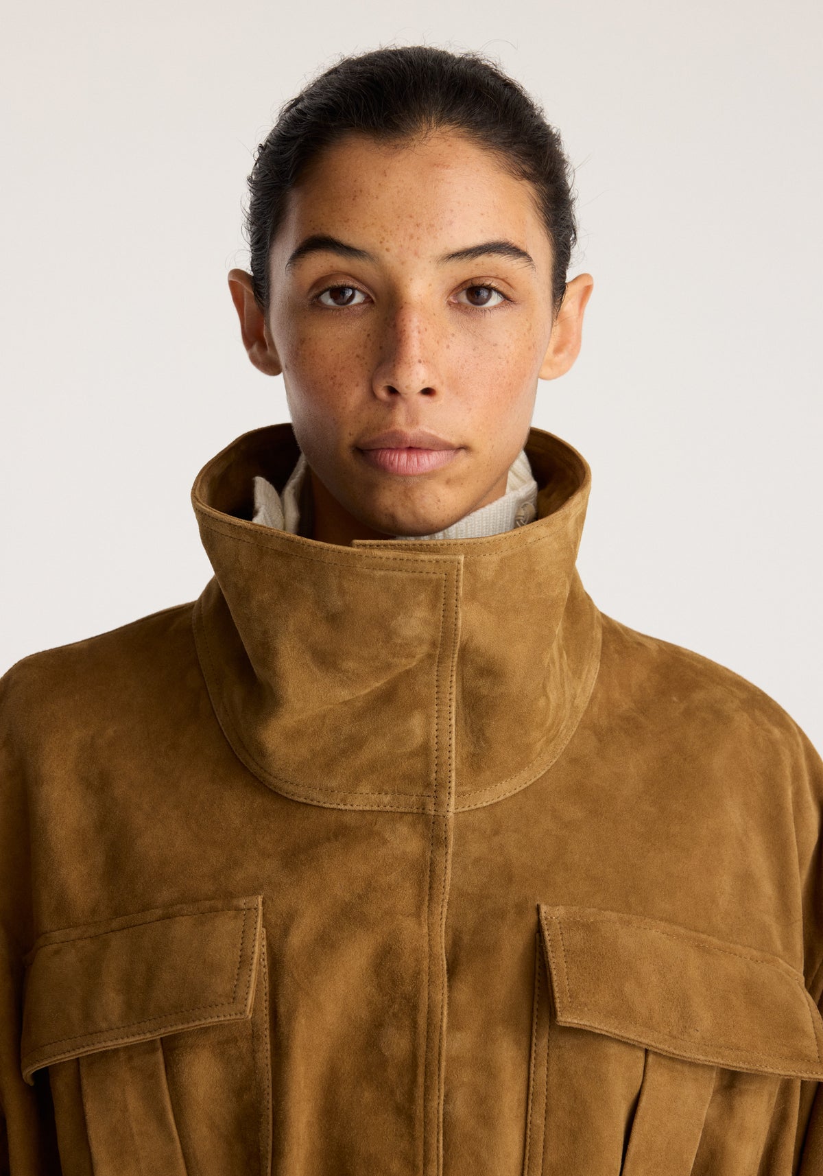 Sculptural suede jacket | sage shown on a model with a sculptural high collar front zip closure and flap pockets