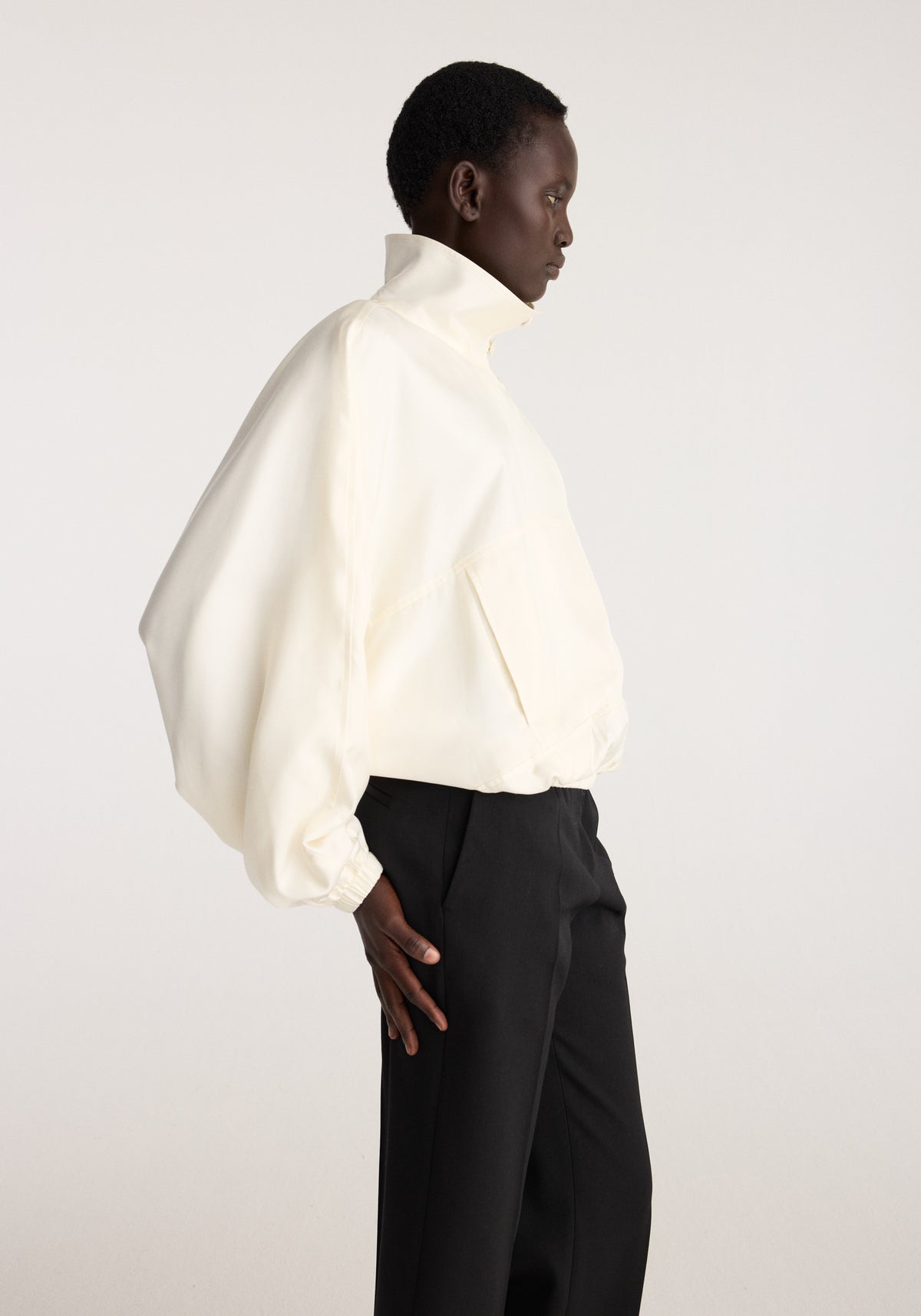 Silk blouson anorak | cream worn by a model in side profile, featuring a high collar, relaxed fit, long sleeves, elastic cuffs, and lightweight fabric