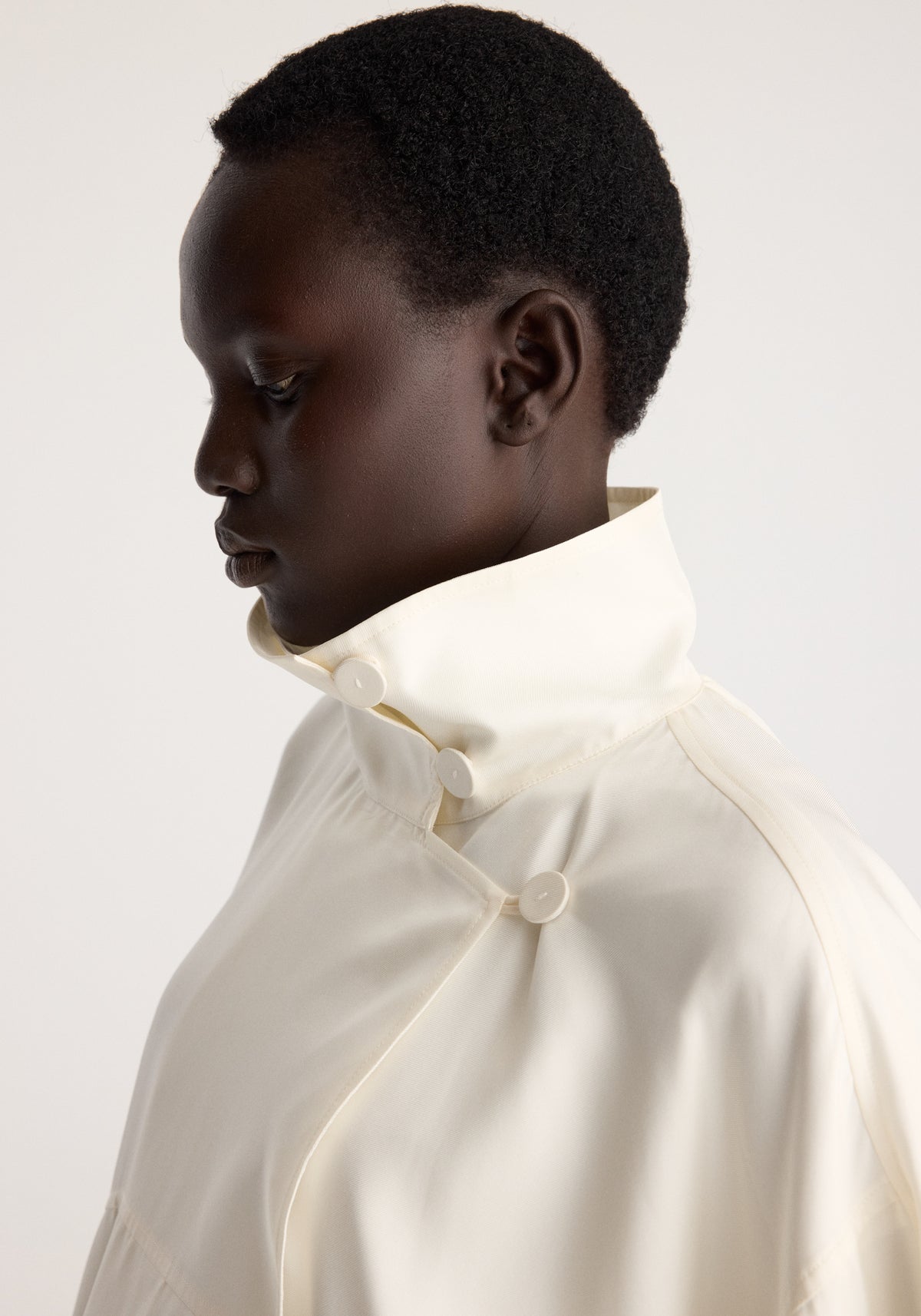 Silk blouson anorak | cream shown in profile on a model with a high buttoned collar and draped cream fabric