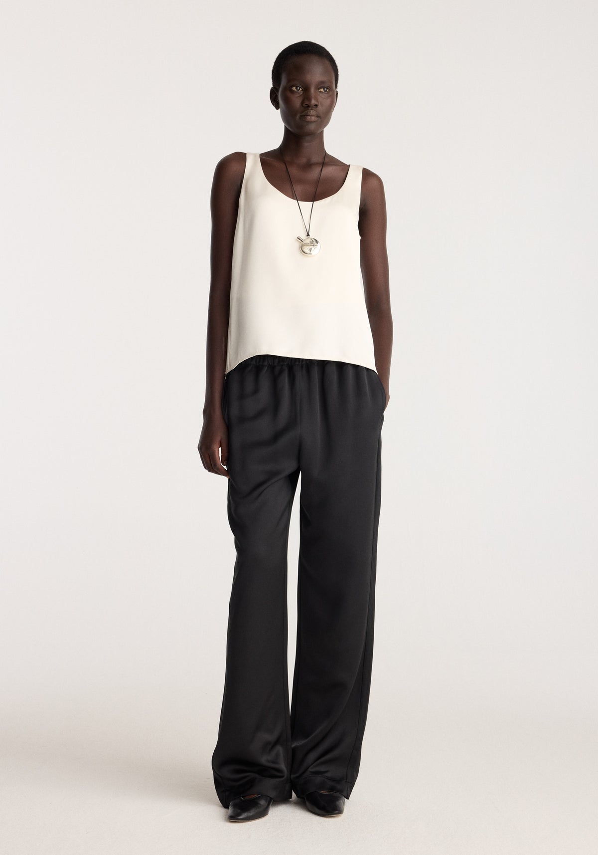 Satin scoop-neck top | ivory worn with black wide-leg trousers and black shoes on a model in a studio setting