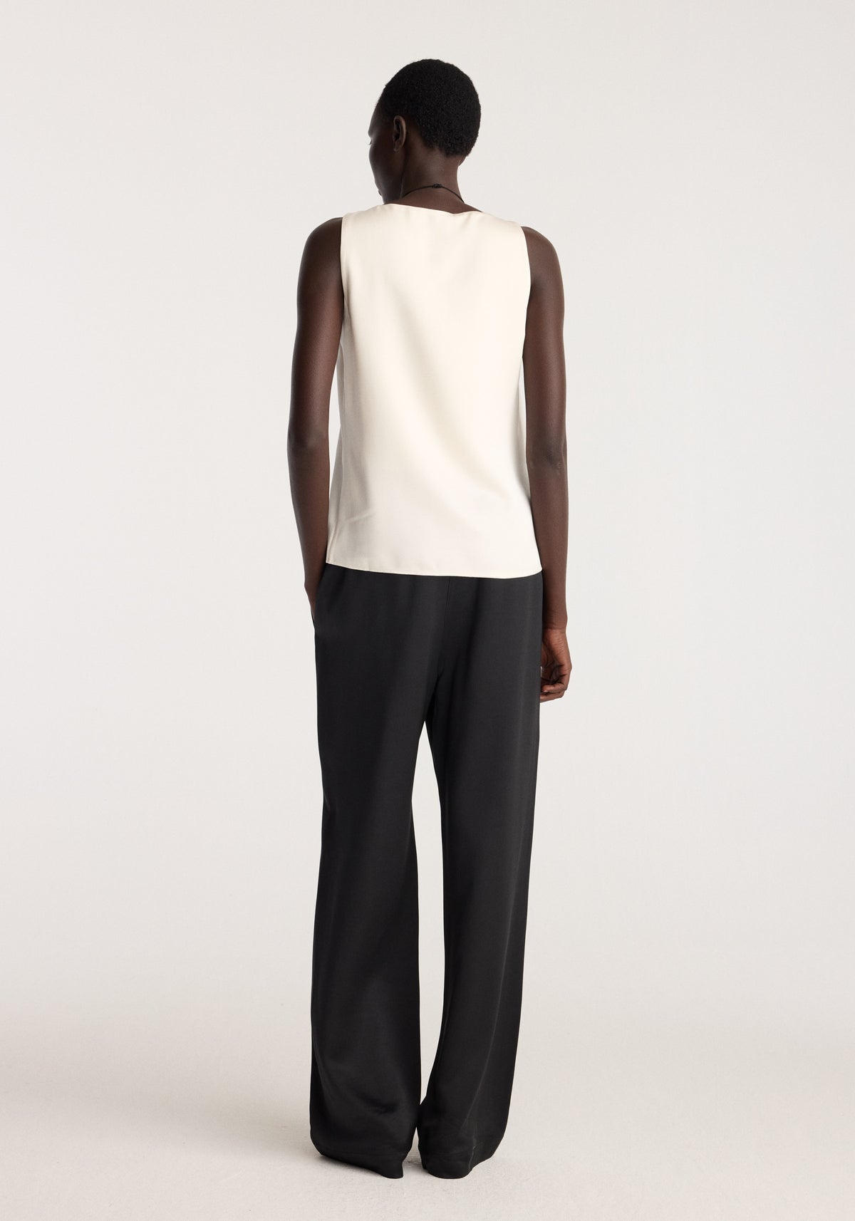 Satin scoop-neck top | ivory shown from the back on a model wearing black trousers with a smooth sleeveless design and relaxed fit