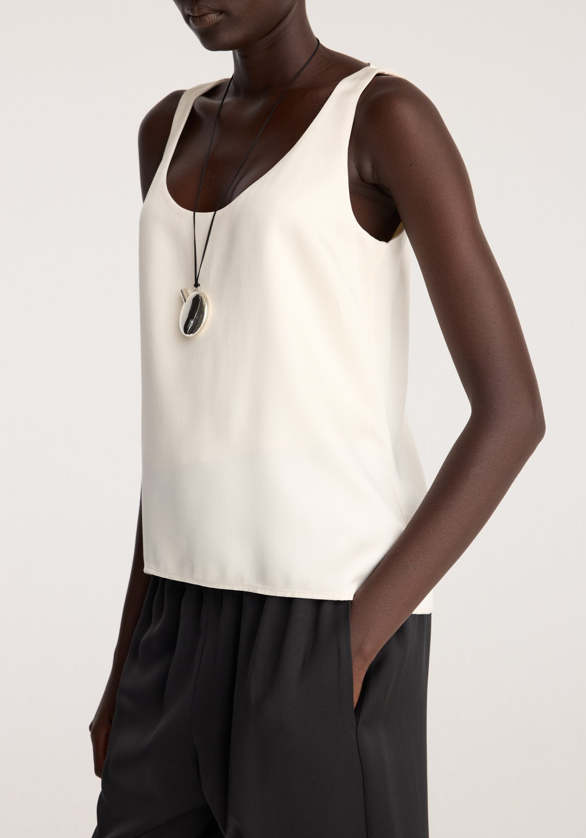 Satin scoop-neck top | ivory worn with black trousers on a model showing the sleeveless scoop neckline and relaxed straight hem