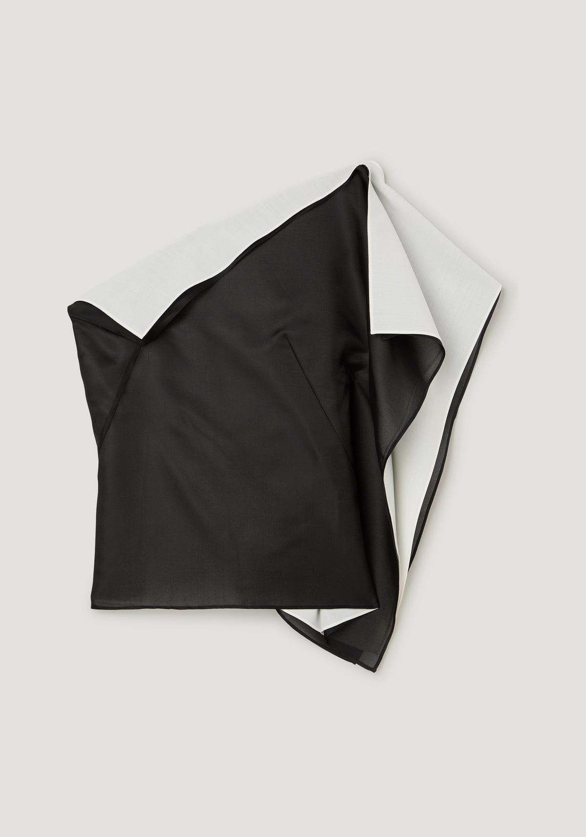Sculptural double layered top | black laid flat, showing its sculptural asymmetrical silhouette and overlapping black layers