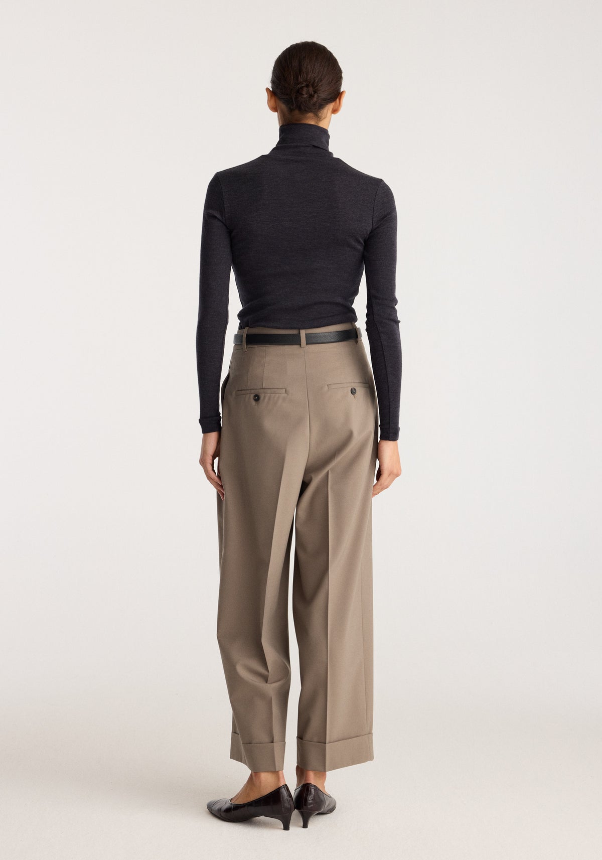 Fine merino turtleneck | anthracite melange shown from the back on a model with tailored taupe trousers and black shoes in a studioાયક