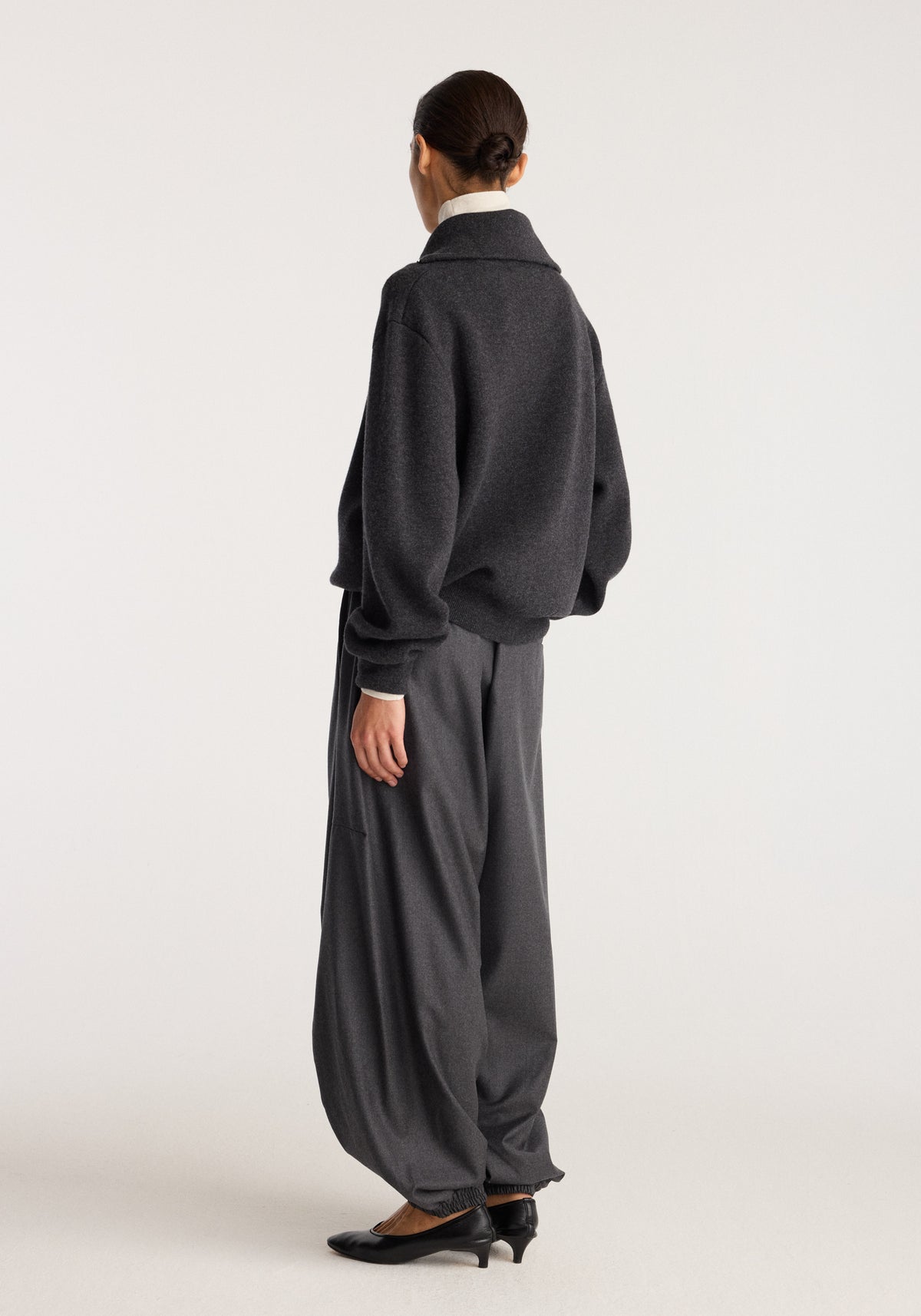 Balloon track pants | dark grey melange shown from the back on a model with a relaxed balloon silhouette and gathered cuffs styled with black shoes