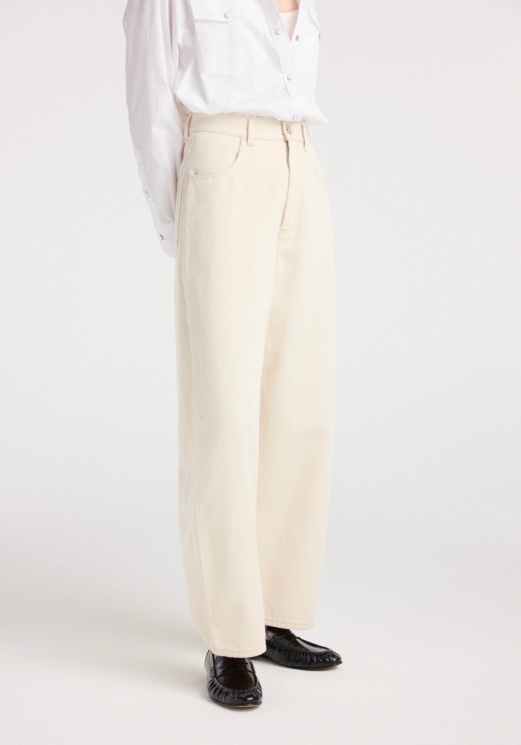 Model wearing Berber - Barrel leg denim | ecru, featuring wide-leg ecru-colored denim pants paired with a white button-up shirt and black shoes, shown against a plain light background.