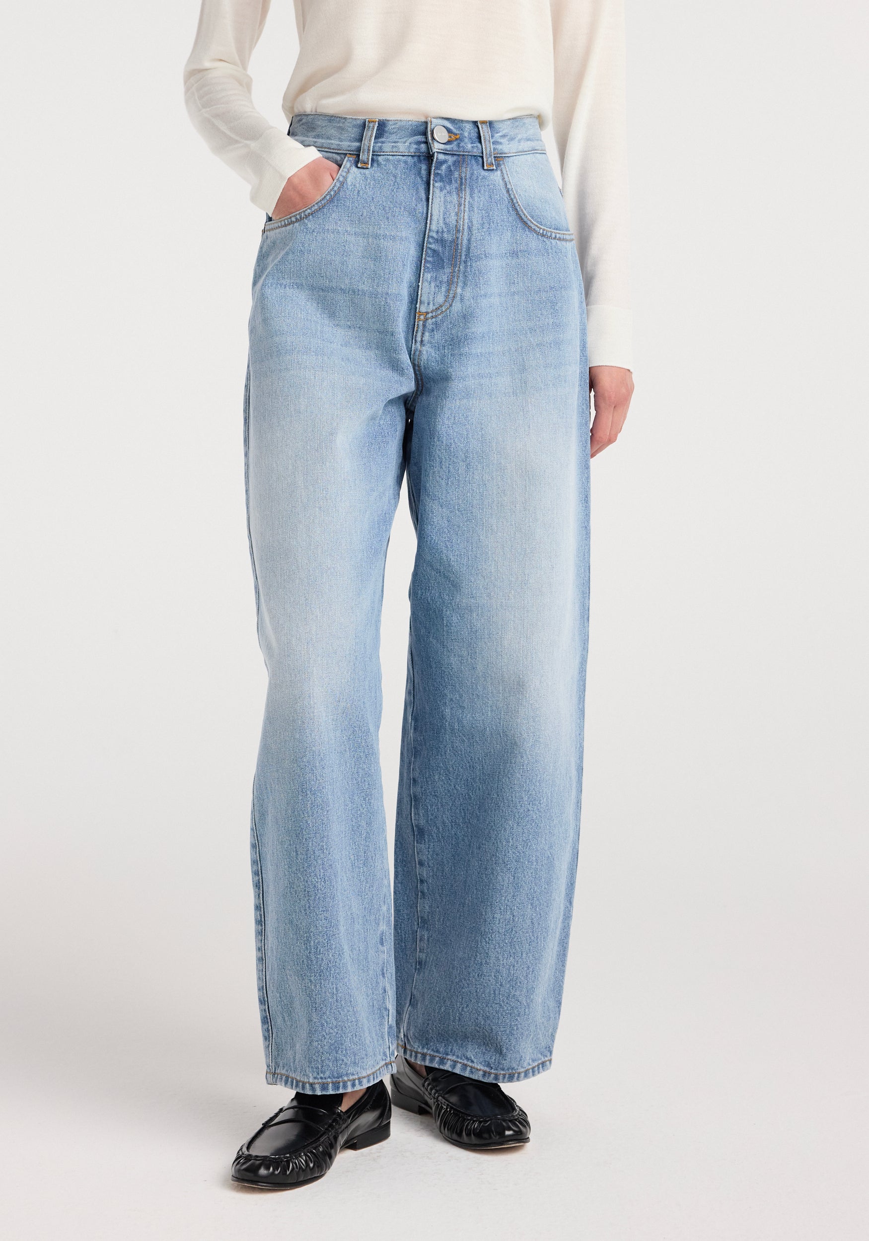 Front view of a person wearing Berber - Barrel leg denim | classic blue jeans paired with a white long-sleeve top and black loafers, standing against a plain background.