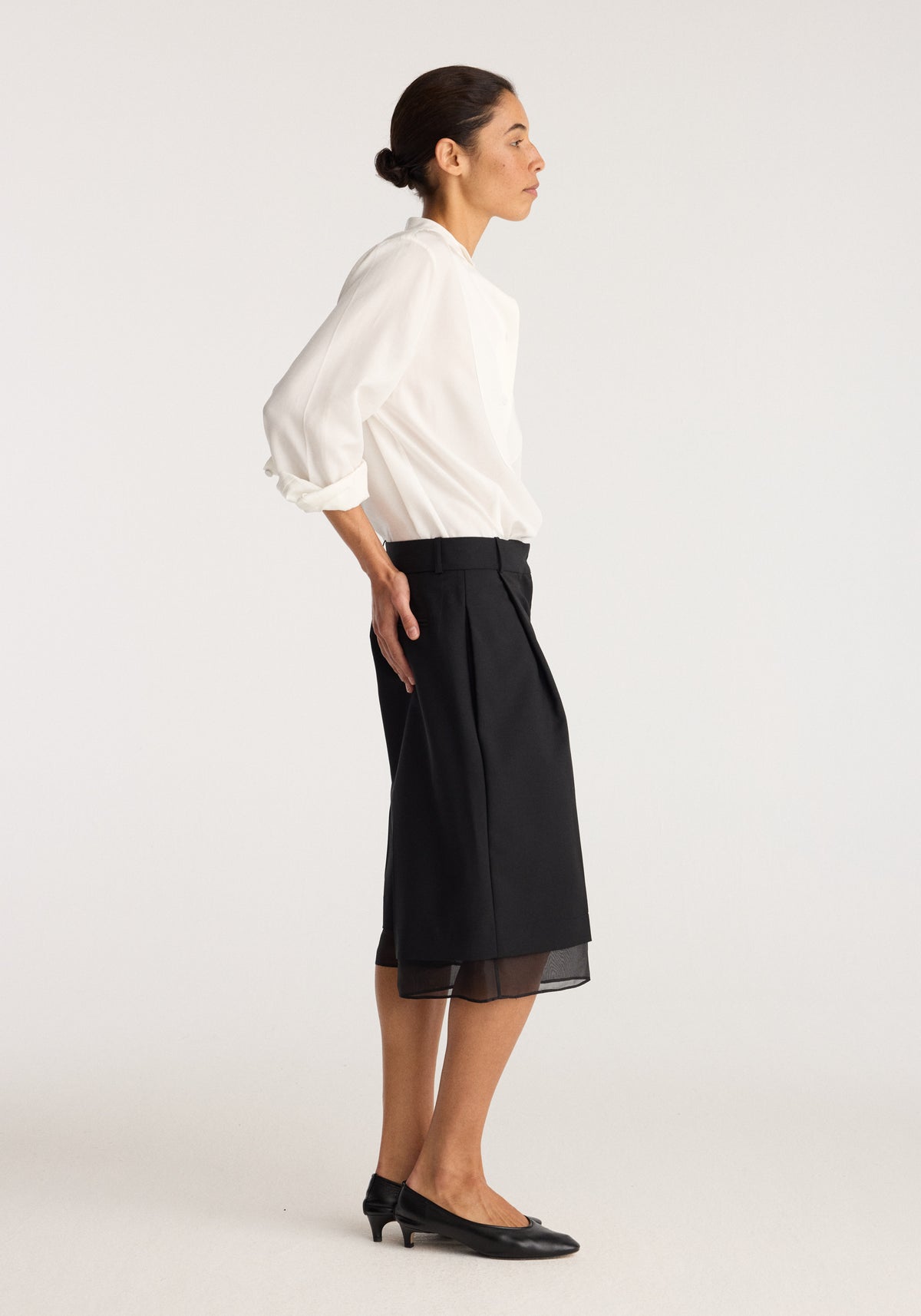 Organza lined shorts | black worn by a model, featuring a relaxed fit, sheer organza hem, and elegant black finish styled with a white blouse and flats