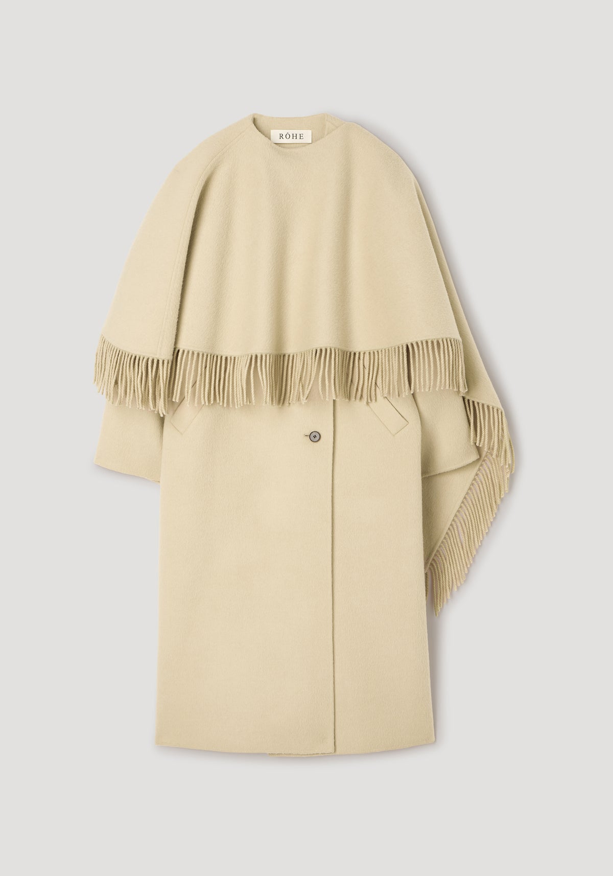 Double-faced fringe coat | butter in a soft beige color with a draped fringe detail over the shoulders and a single button closure, displayed on a neutral background.