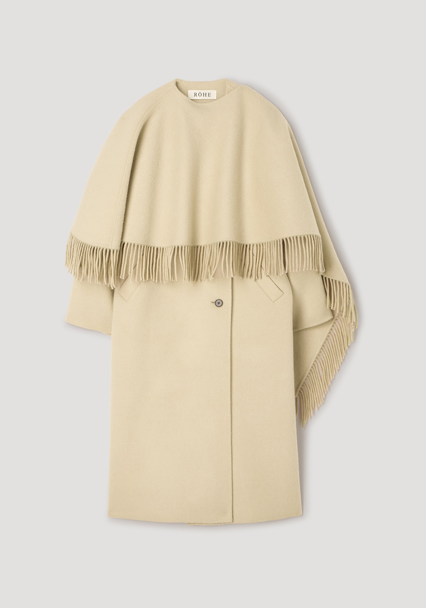 Double-faced fringe coat | butter in a soft beige color with a draped fringe detail over the shoulders and a single button closure, displayed on a neutral background.