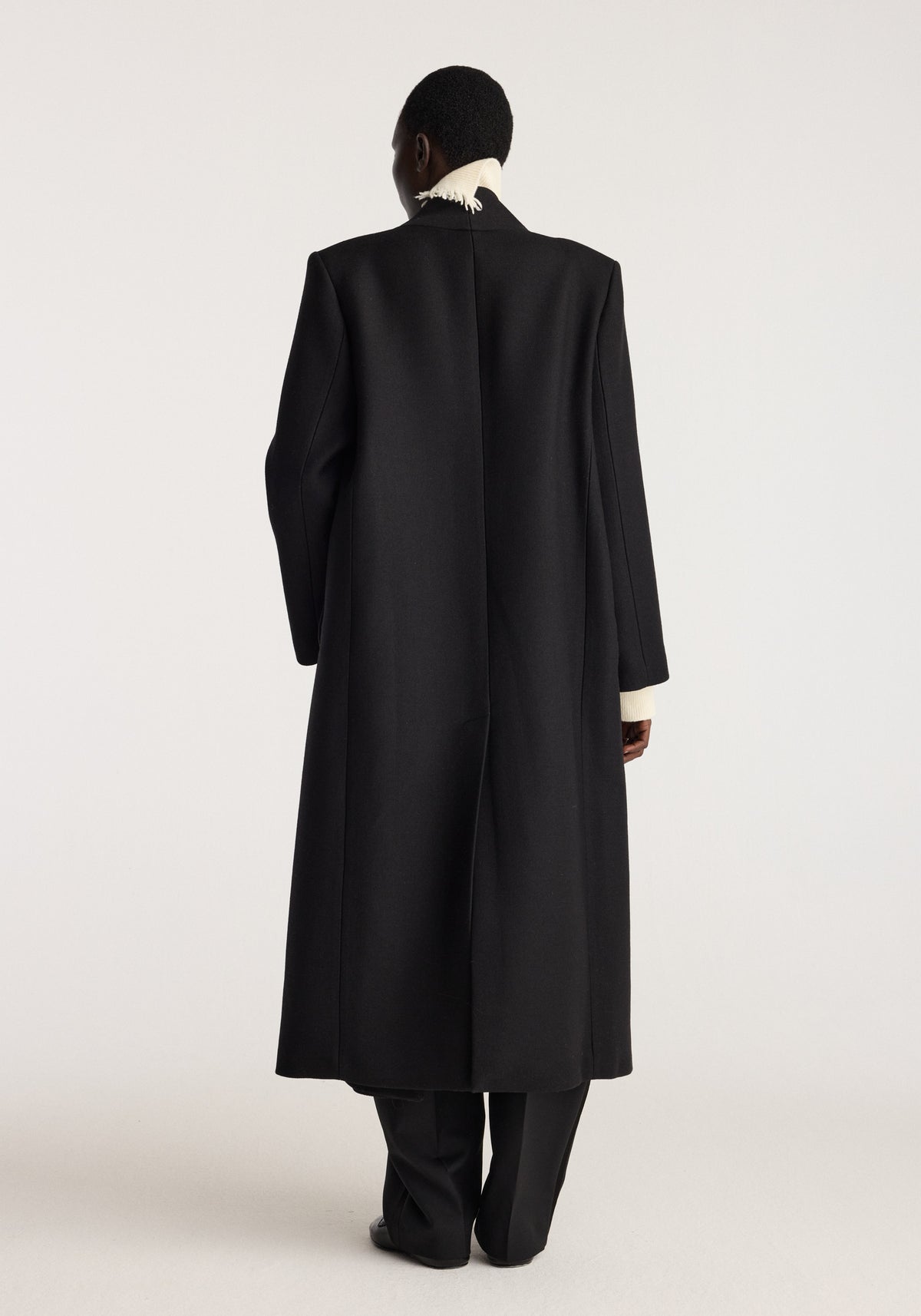 Pankou closure wool coat | black shown from the back on a model with a long tailored silhouette high collar and full length sleeves