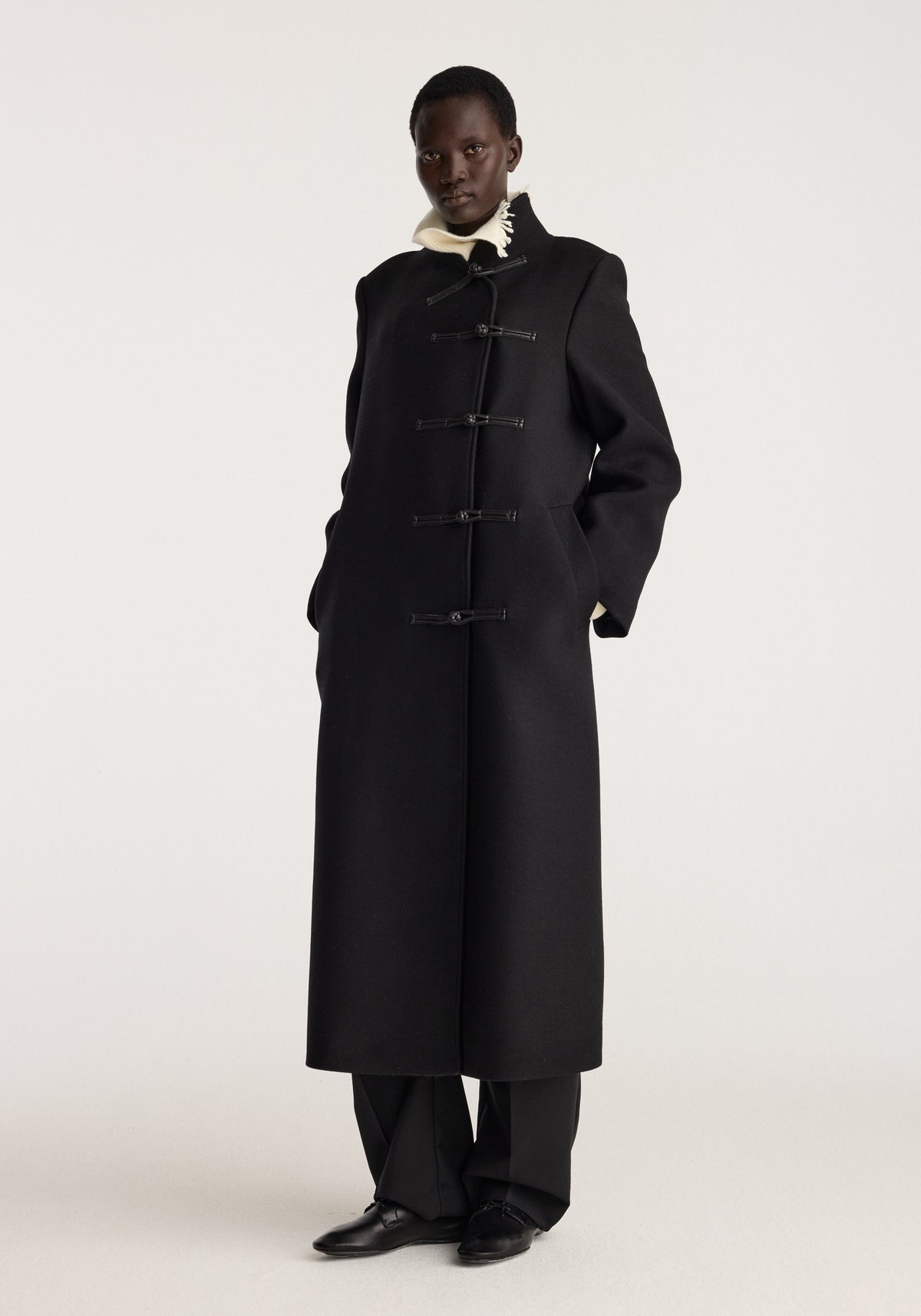 Pankou closure wool coat | black shown on a model with a full length silhouette and traditional toggle closures worn over dark trousers and shoes