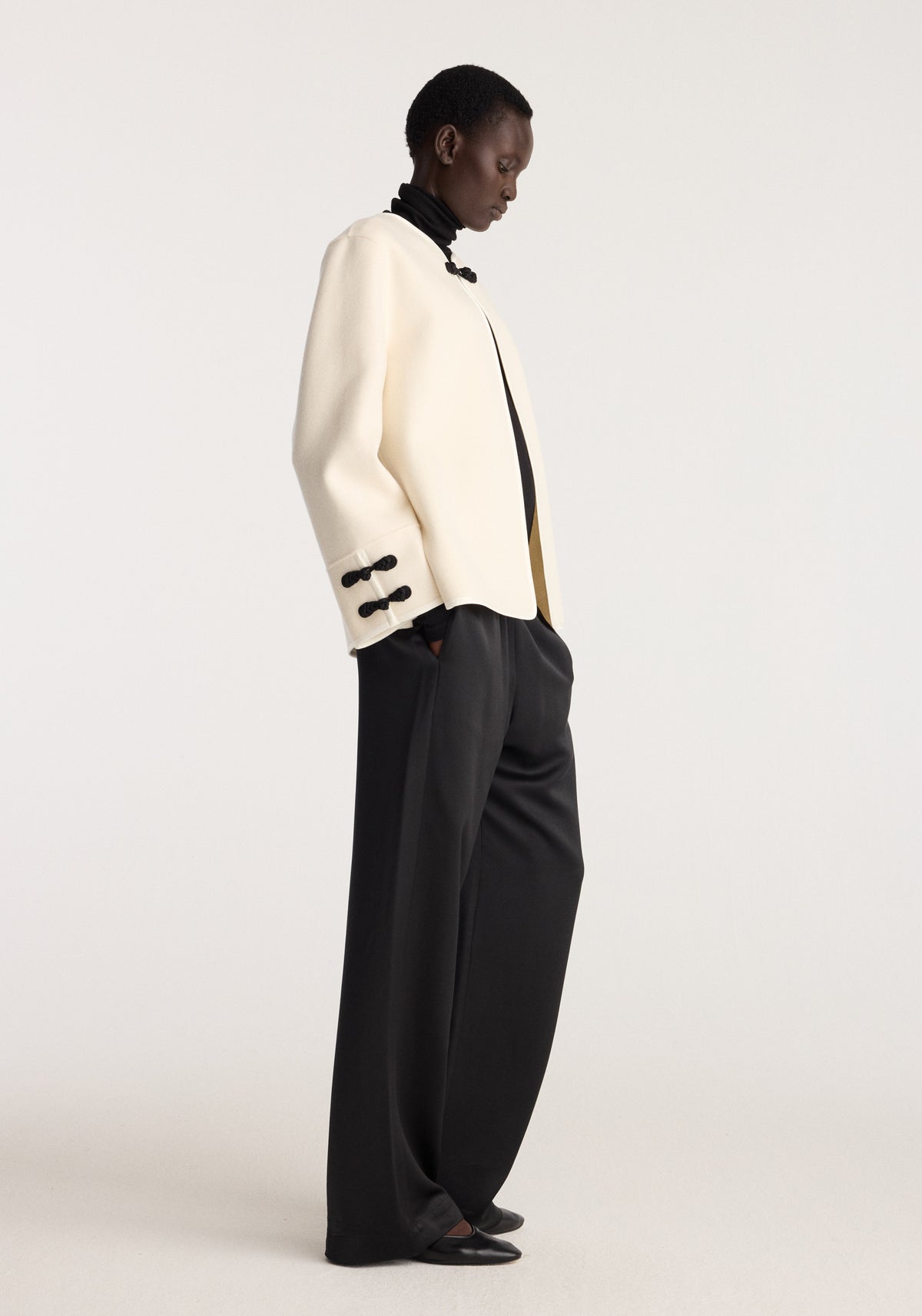 Double-faced pankou jacket | off white worn with black trousers and loafers in a side profile studio portrait showing the contrasting collar and sleeve closures