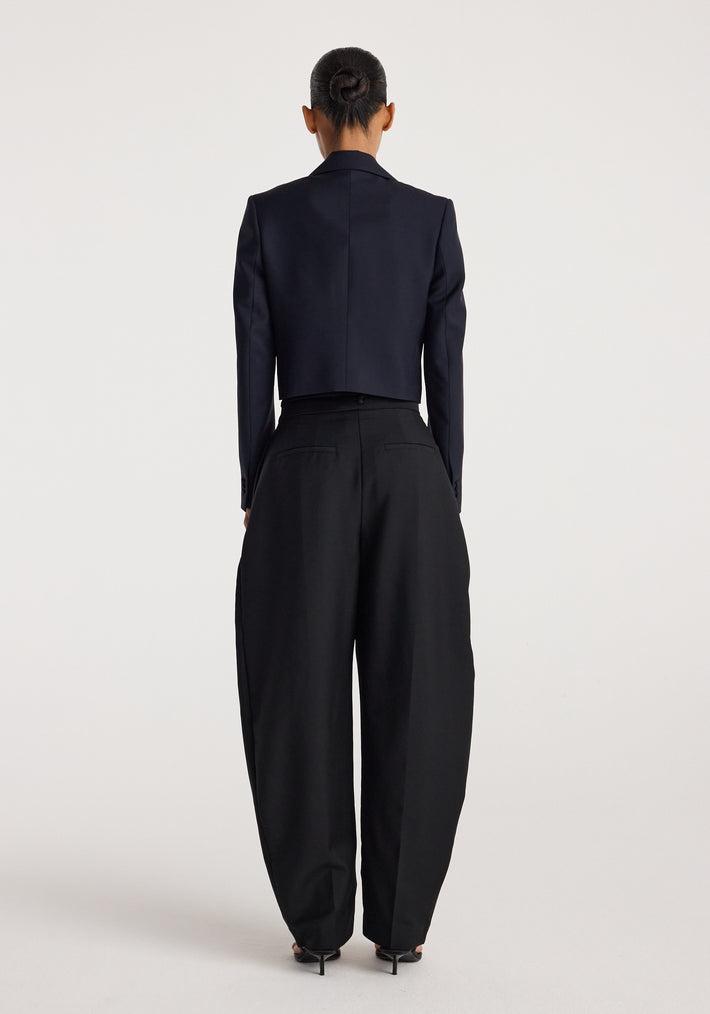 Woman seen from behind wearing a tailored Cropped blazer | navy paired with high-waisted, wide-leg black trousers and black heels against a plain background