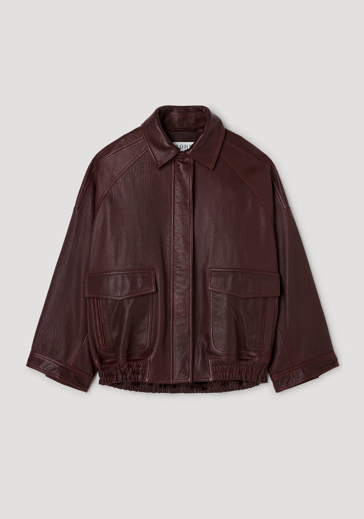 Grain leather aviator jacket | chestnut in rich dark brown with textured finish, featuring a classic collar, front flap pockets, and elasticized hem, laid flat on a light background.