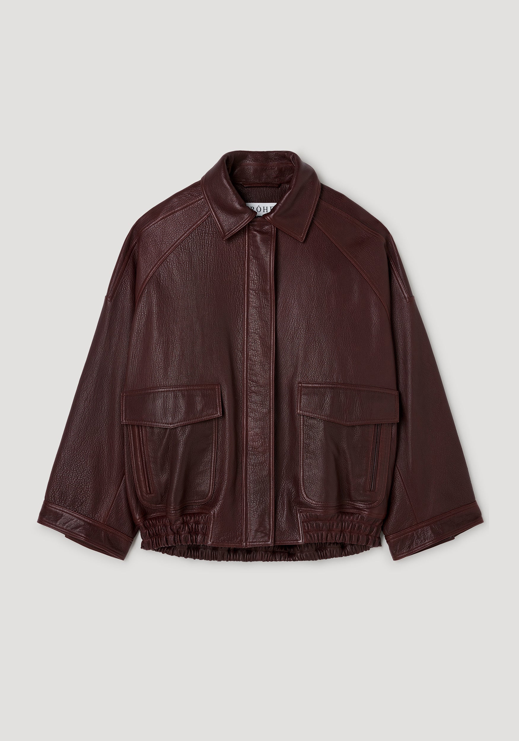 Grain leather aviator jacket | chestnut in rich dark brown with textured finish, featuring a classic collar, front flap pockets, and elasticized hem, laid flat on a light background.