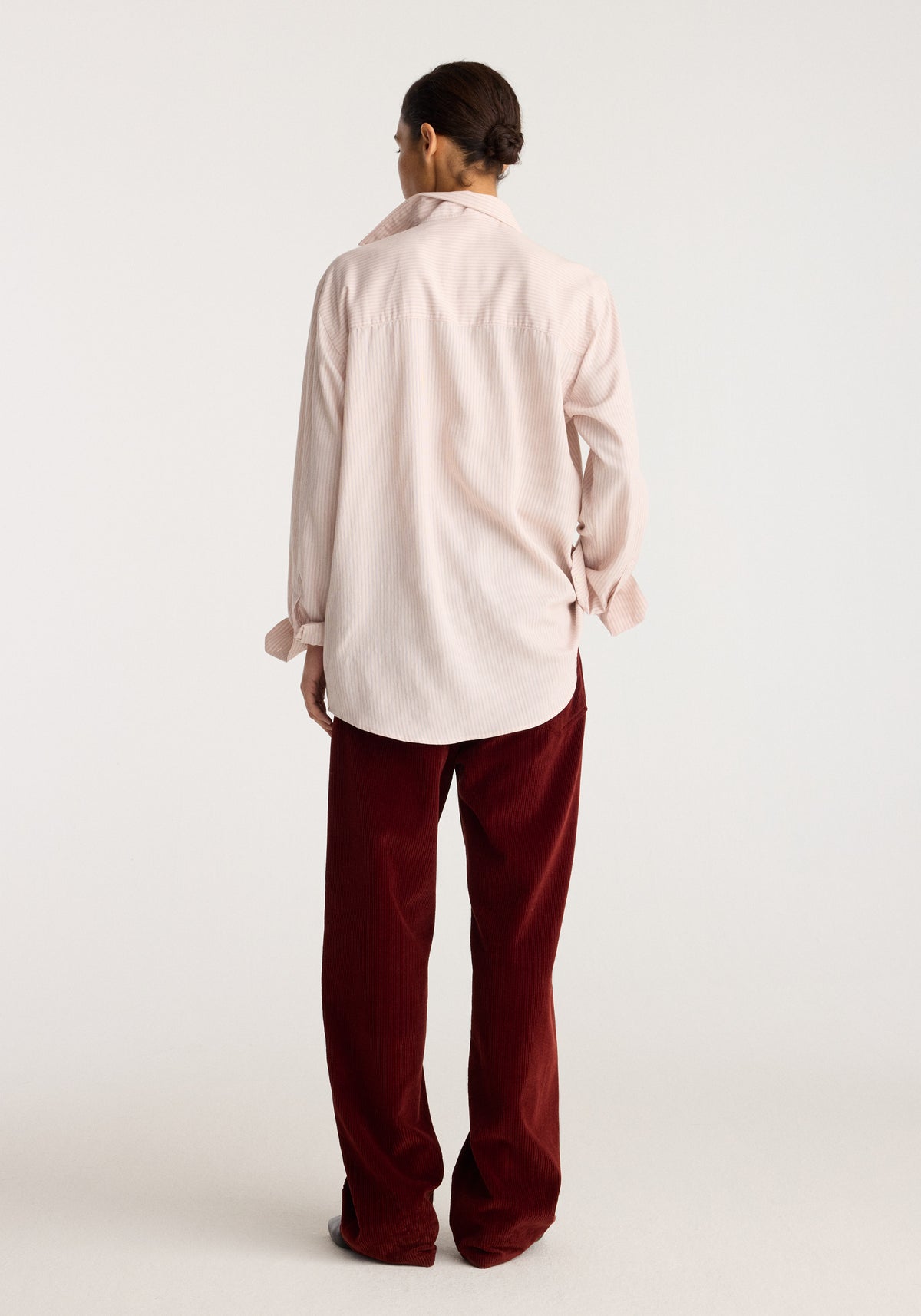 Classic fit striped shirt | rose stripe shown from the back on a model with long sleeves and a curved hem in a pale rose striped pattern