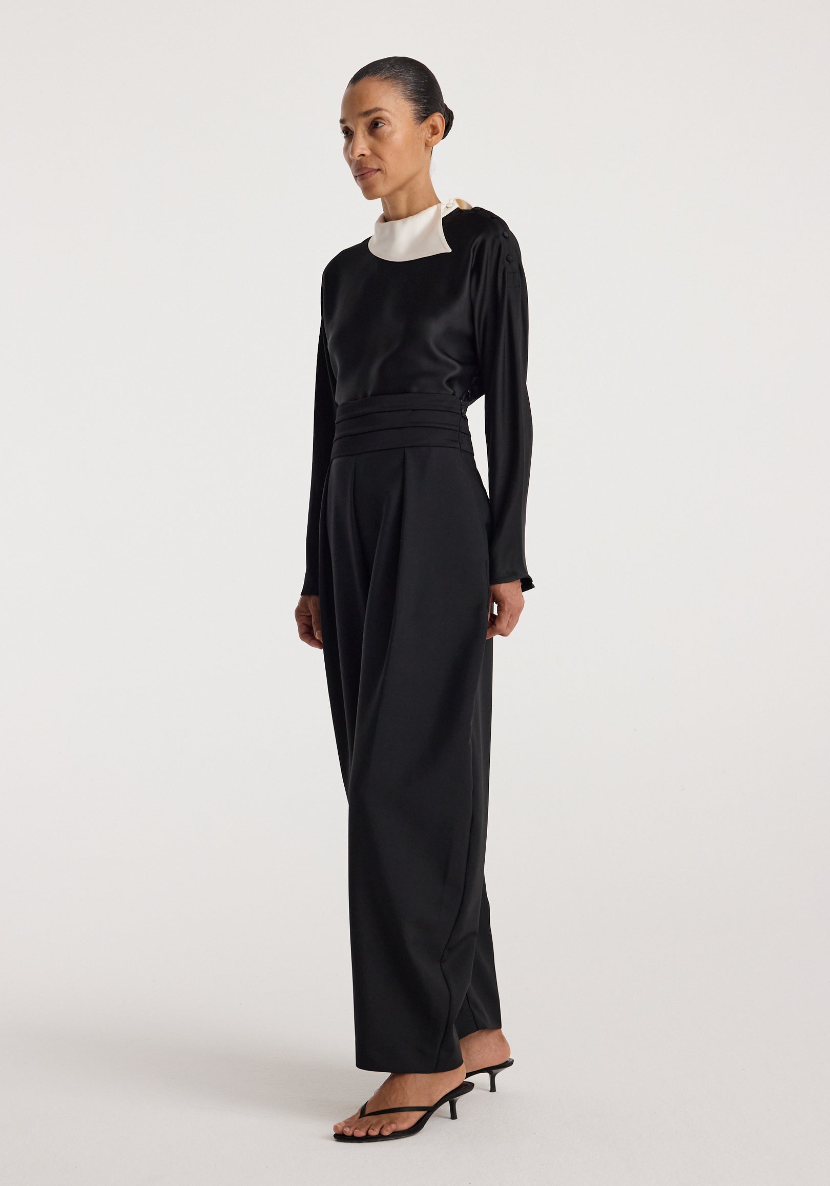 Woman wearing a black long-sleeve top with a unique white collar detail and wide-leg black pants, styled with black heeled sandals, showcasing the Reimagined collar top | black.