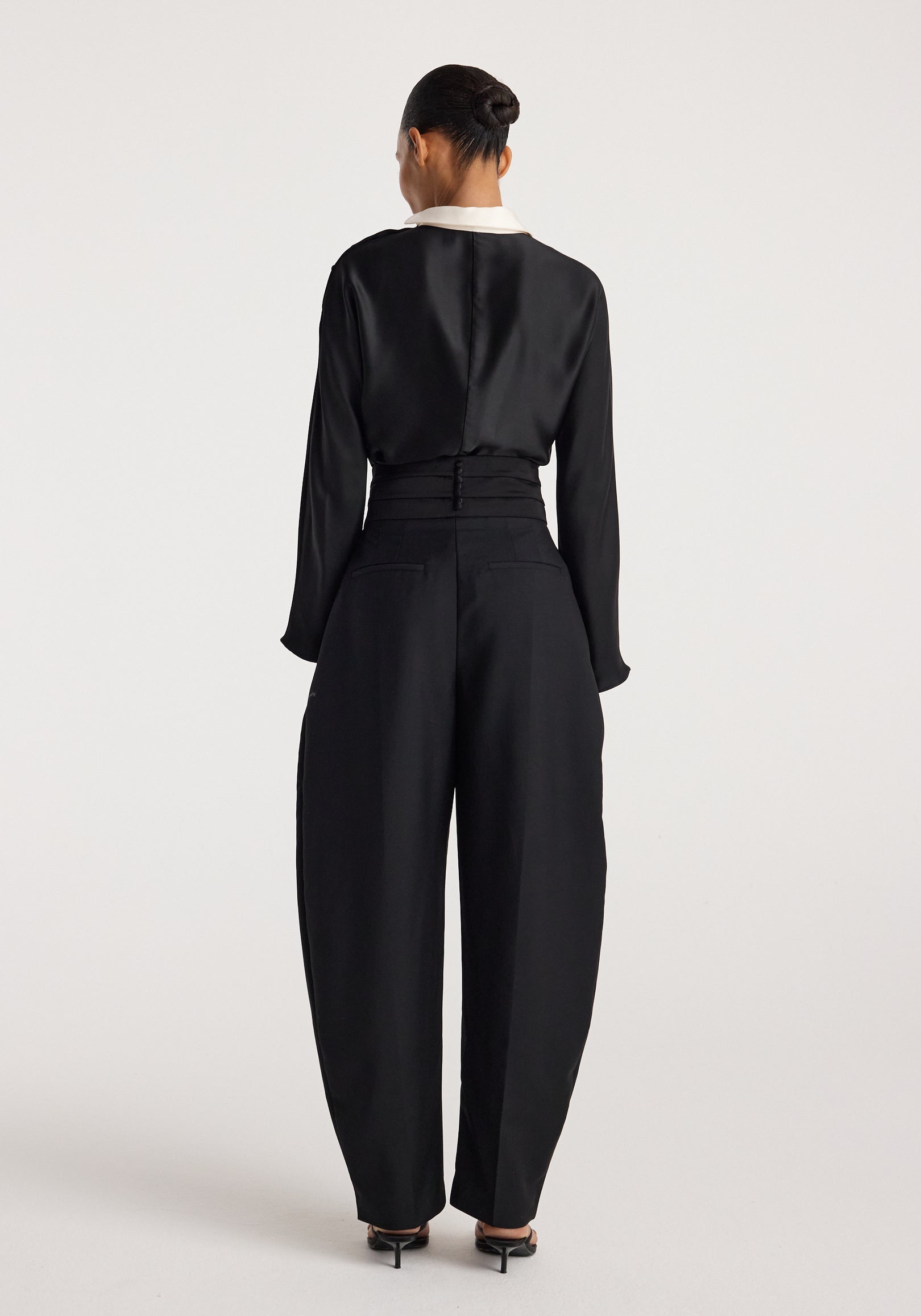 Woman wearing black high-waisted wide-leg trousers and a black long-sleeve Reimagined collar top | black with white collar, shown from the back against a plain background.
