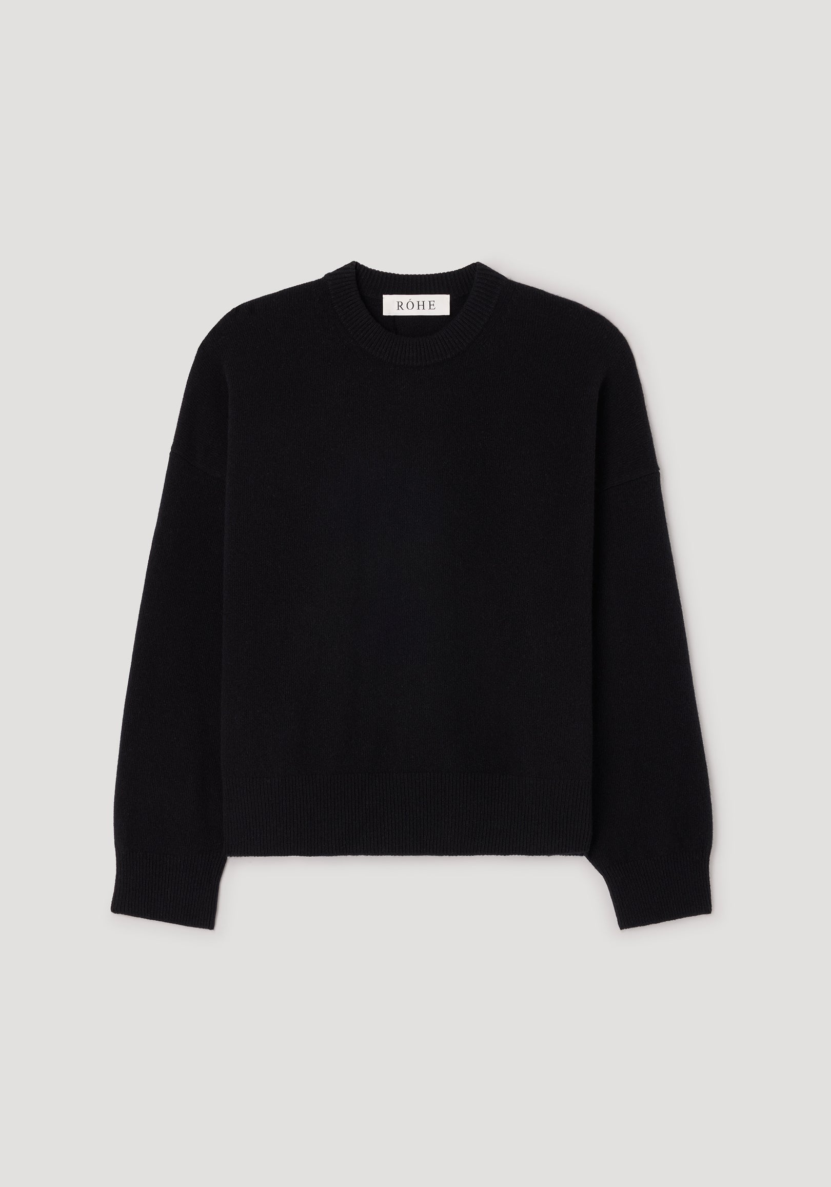 Classic crewneck jumper | black laid flat on a light background, featuring a simple and timeless design with long sleeves and ribbed edges at the neckline, cuffs, and hem.