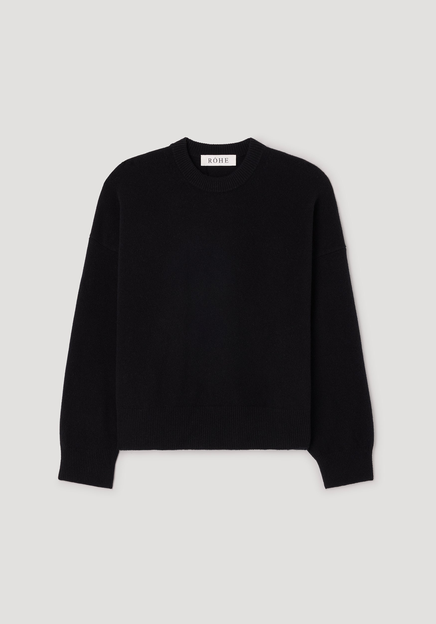 Classic crewneck jumper | black laid flat on a light background, featuring a simple and timeless design with long sleeves and ribbed edges at the neckline, cuffs, and hem.