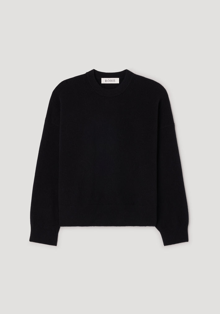 Classic crewneck jumper | black laid flat on a light background, featuring a simple and timeless design with long sleeves and ribbed edges at the neckline, cuffs, and hem.