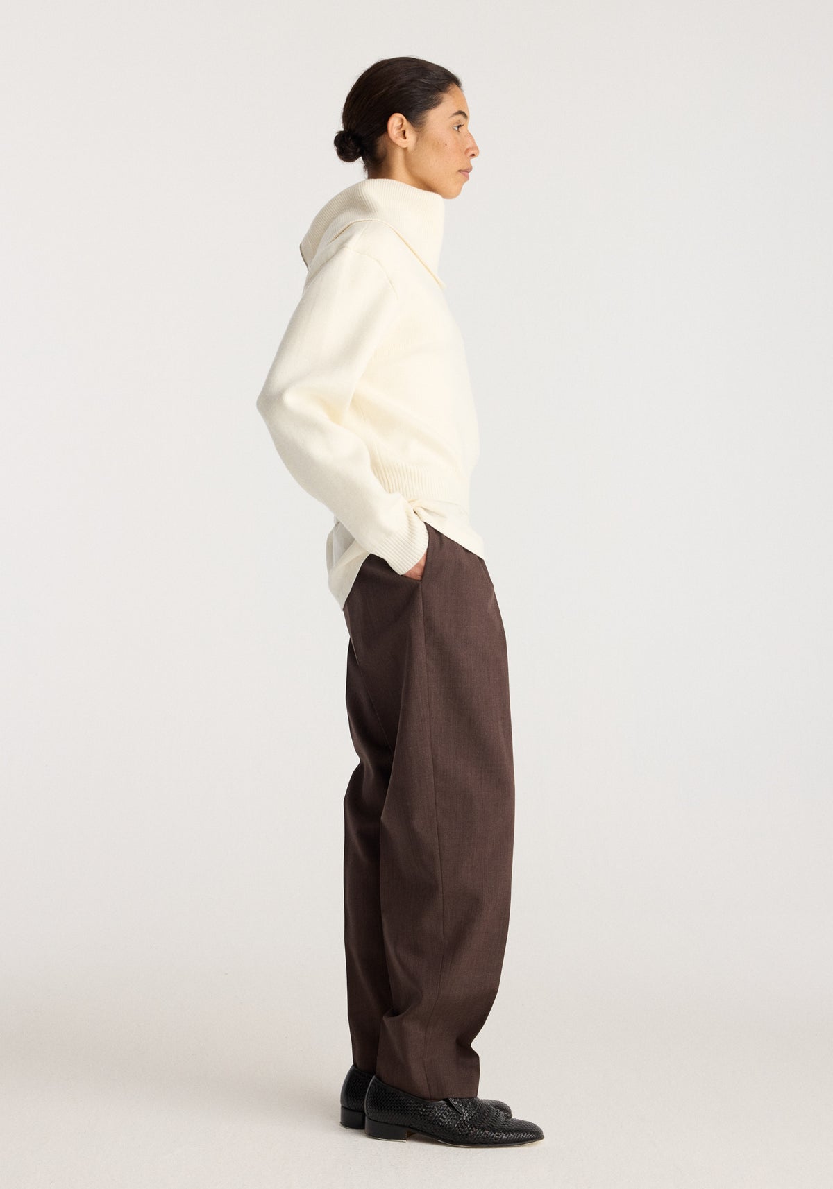 Reversible sailor zip cardigan | cream shown in side profile on a model with brown trousers and black shoes against a neutral studio background