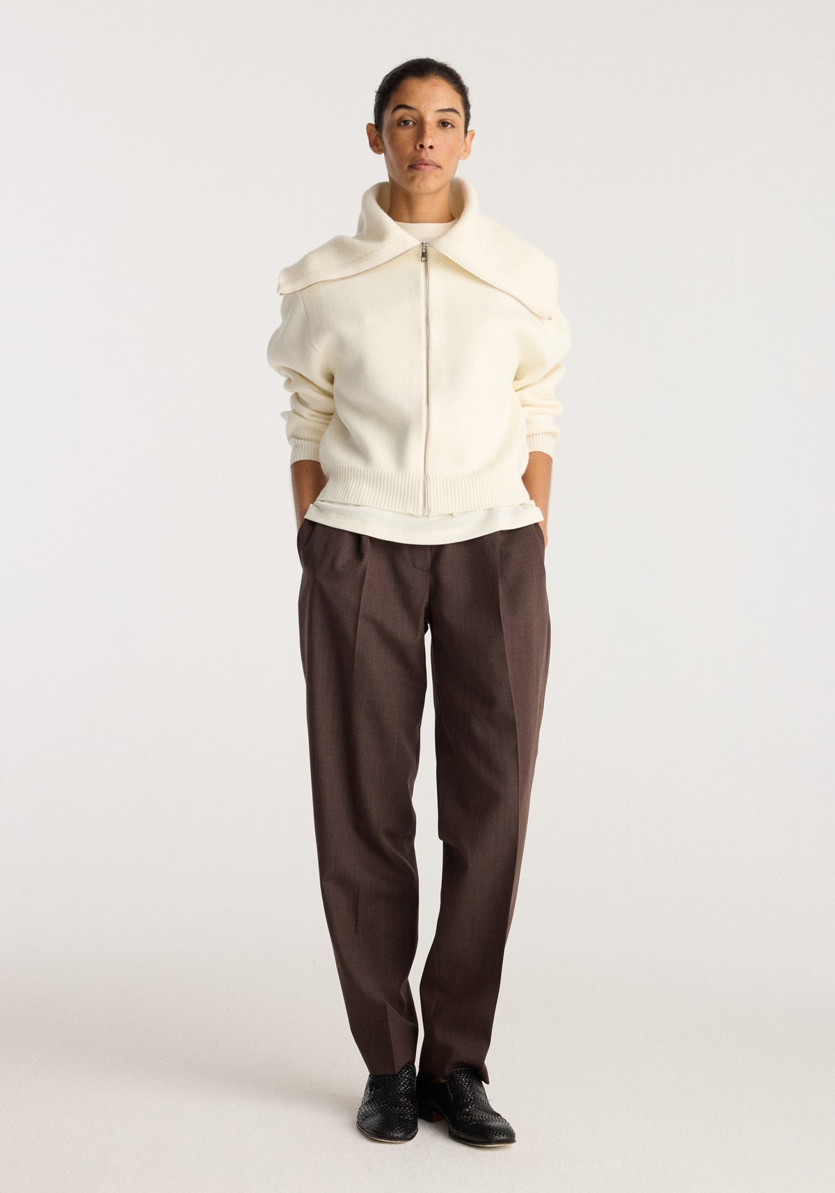 Reversible sailor zip cardigan | cream worn by a model with a high collar zip front and relaxed fit styled with brown trousers and black shoes