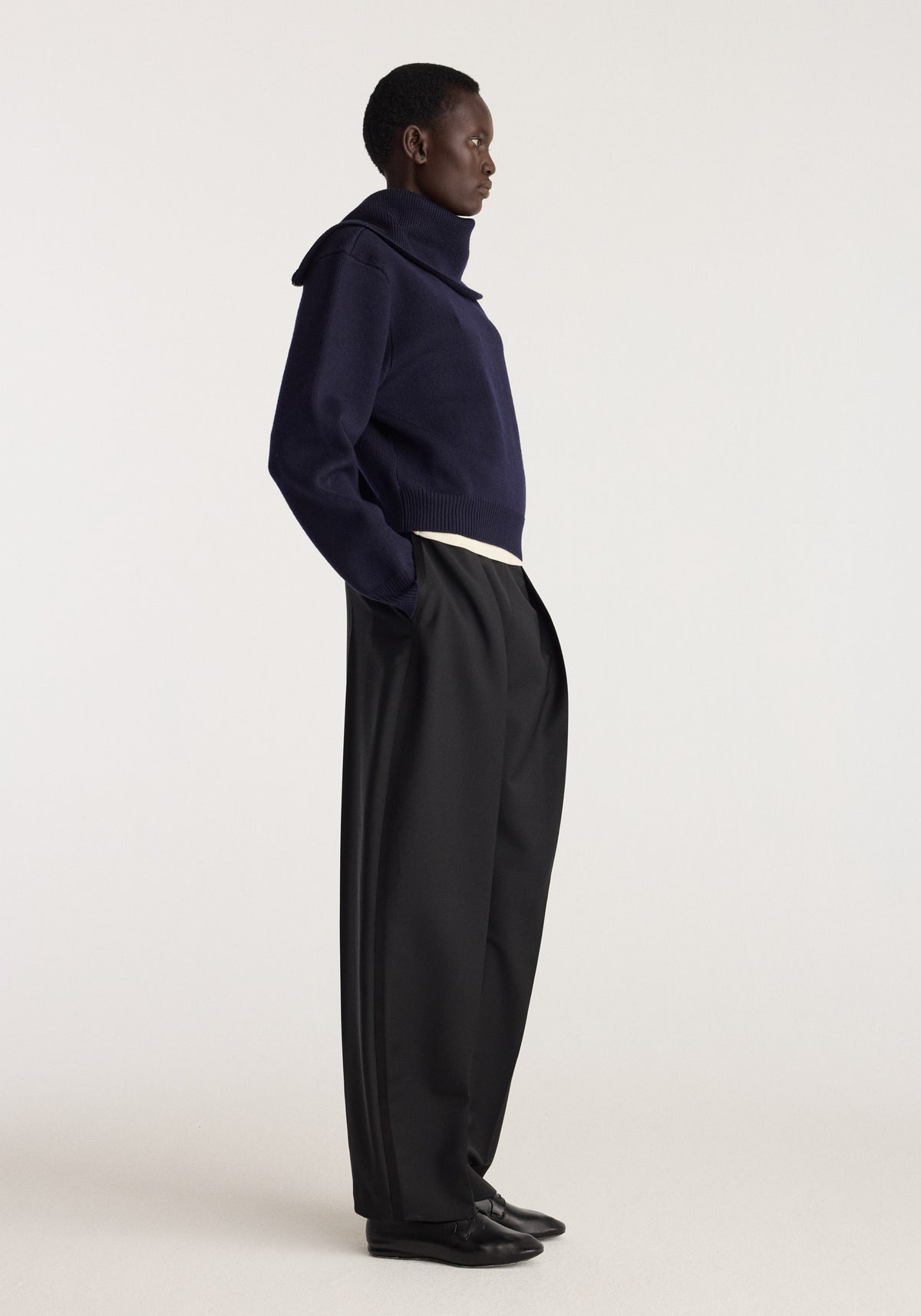 Reversible sailor zip cardigan | navy worn by a model in side profile with black trousers and shoes against a light studio background