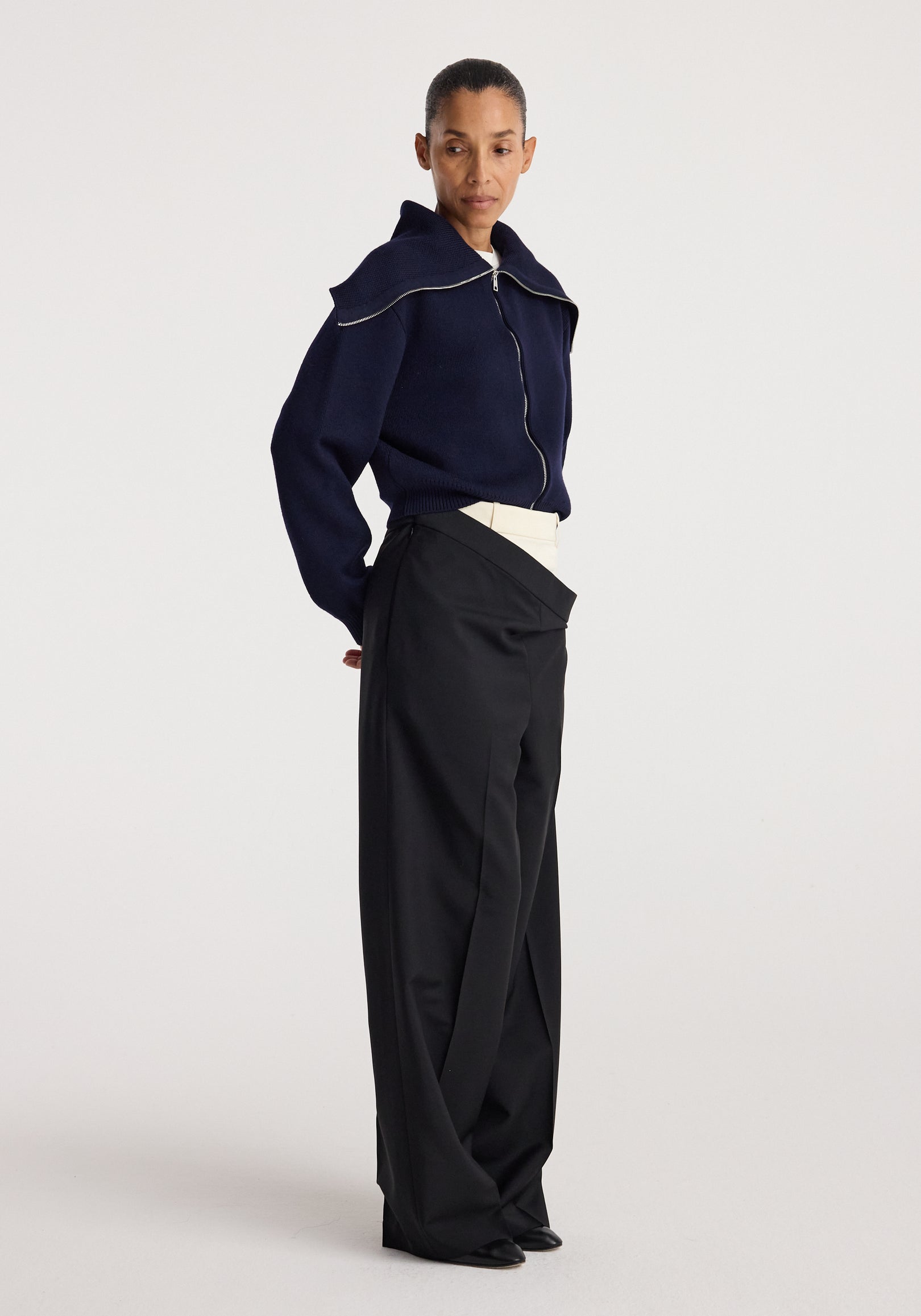 Woman wearing a navy zip-up cardigan with a sailor collar paired with high-waisted black wide-leg pants, styled in a minimalist fashion look, featuring the Two way sailor zip cardigan | navy.