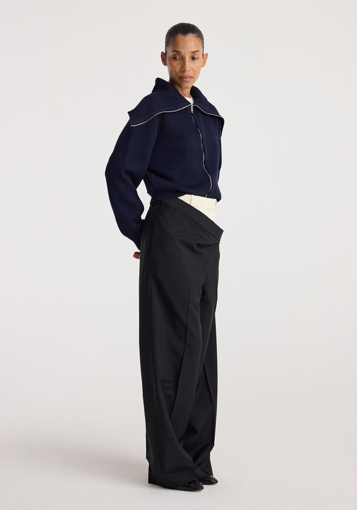 Woman wearing a navy zip-up cardigan with a sailor collar paired with high-waisted black wide-leg pants, styled in a minimalist fashion look, featuring the Two way sailor zip cardigan | navy.
