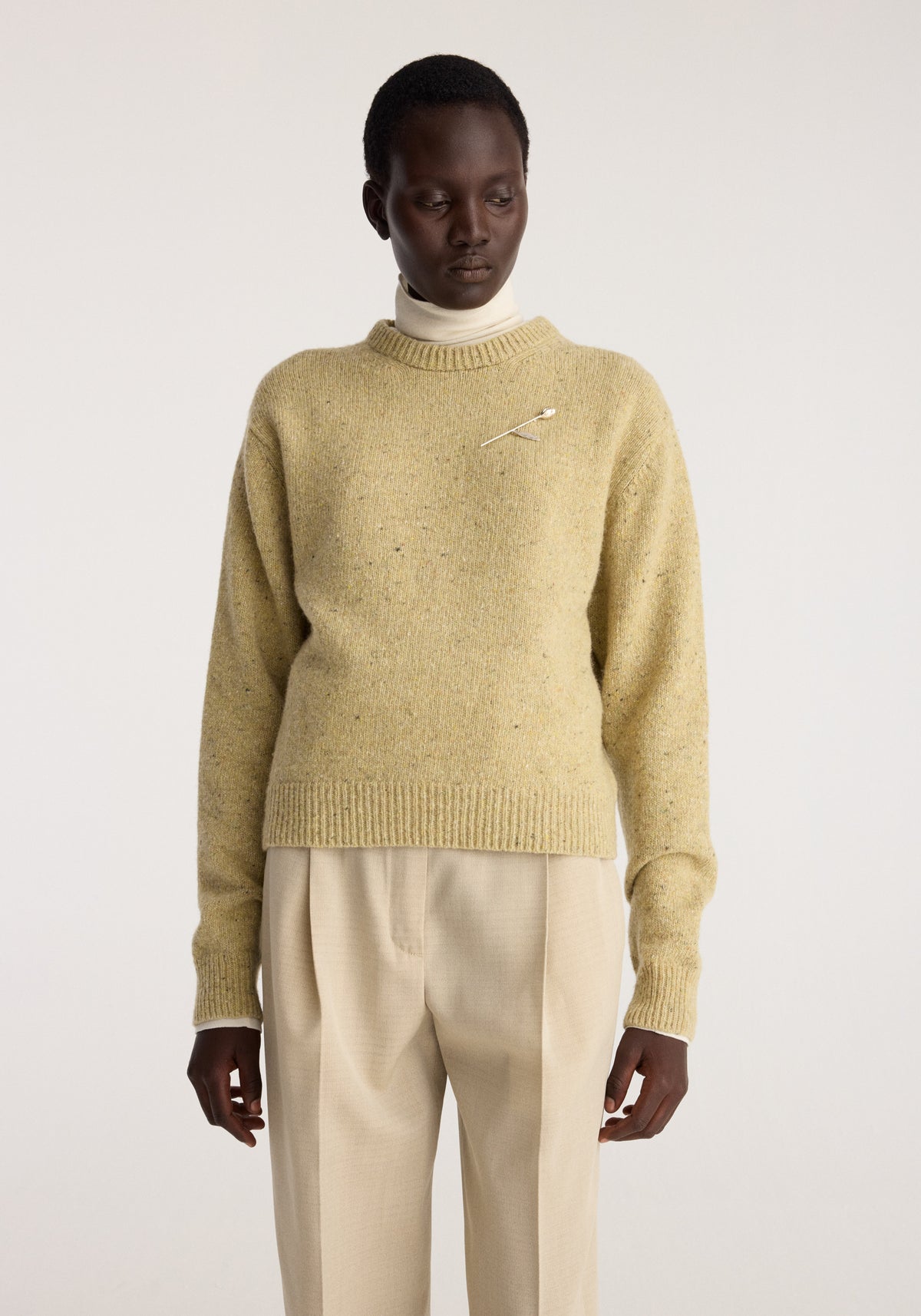 A model wears the Fitted mouliné crewneck | butter mouliné in a warm butter yellow knit with ribbed cuffs and hem.