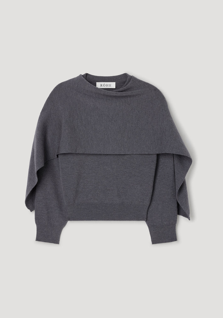 Dark grey melange knitted cape jumper with long sleeves, ribbed cuffs and hem, featuring a layered cape design for a stylish and cozy look. Cape jumper | dark grey melange