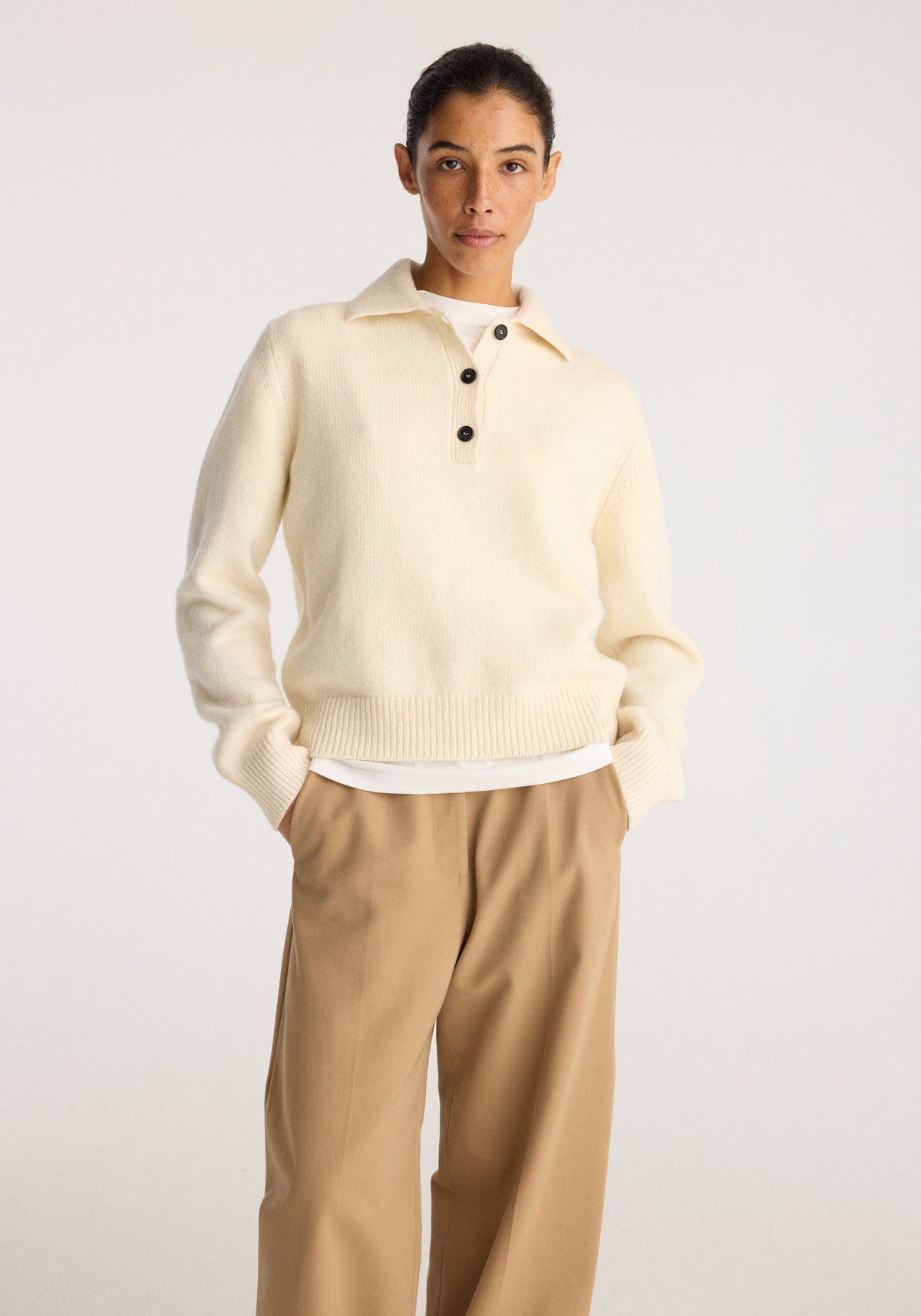 Wool-cashmere polo | cream worn by a model with a collared neckline and button placket styled with wide leg beige trousers