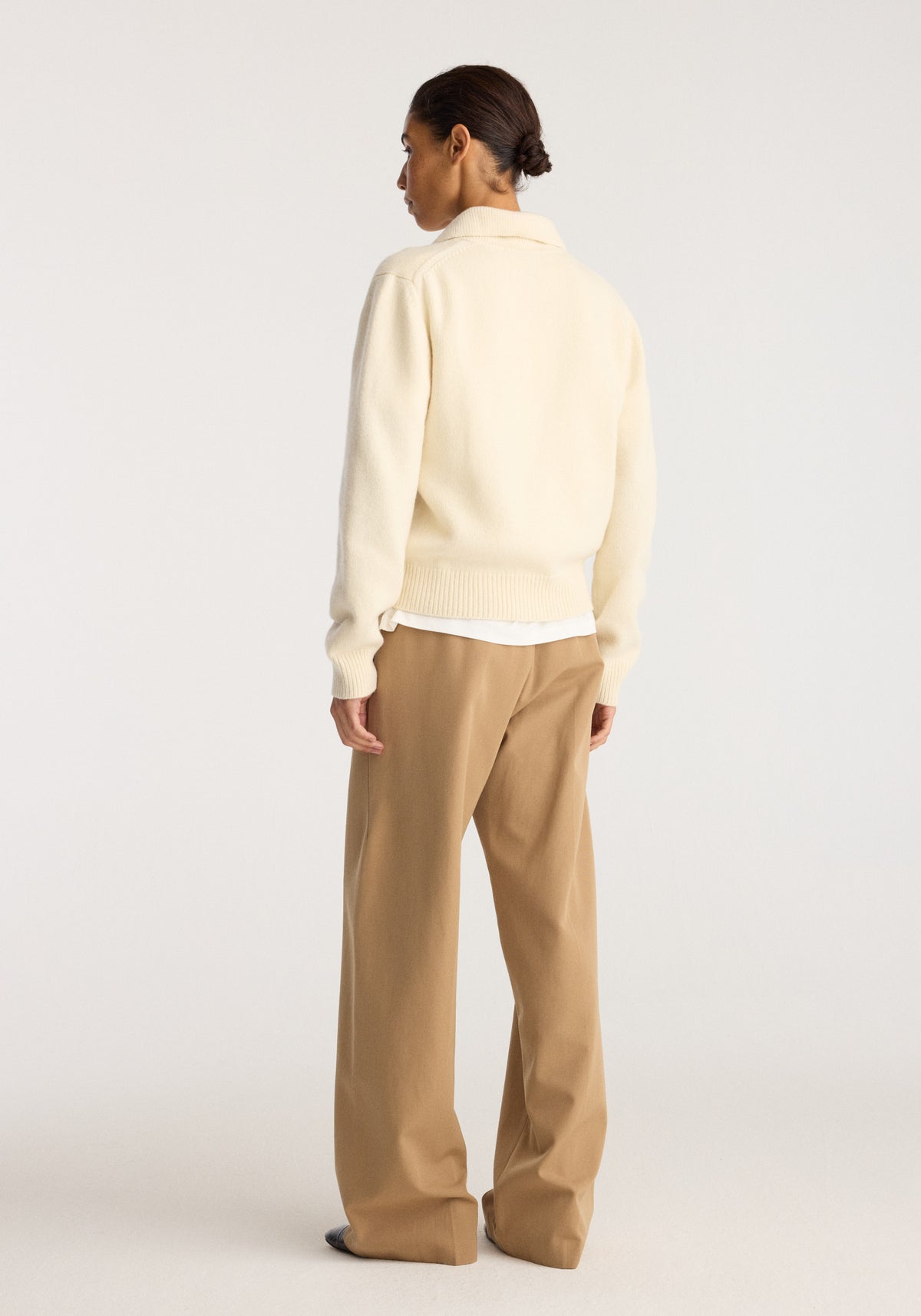 Wool-cashmere polo | cream shown from the back on a model, featuring a relaxed fit, long sleeves, ribbed hem and collar, styled with tan trousers.