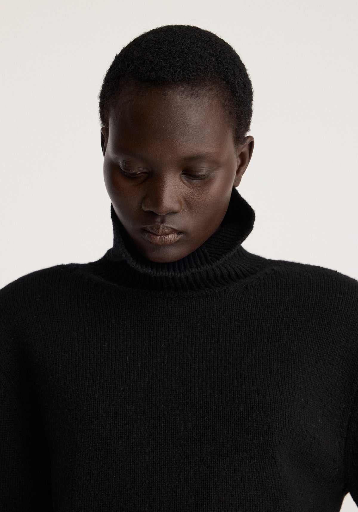 Statement shoulder turtleneck | black worn by a model, featuring a high ribbed neck, relaxed shoulders, and a soft black knit finish