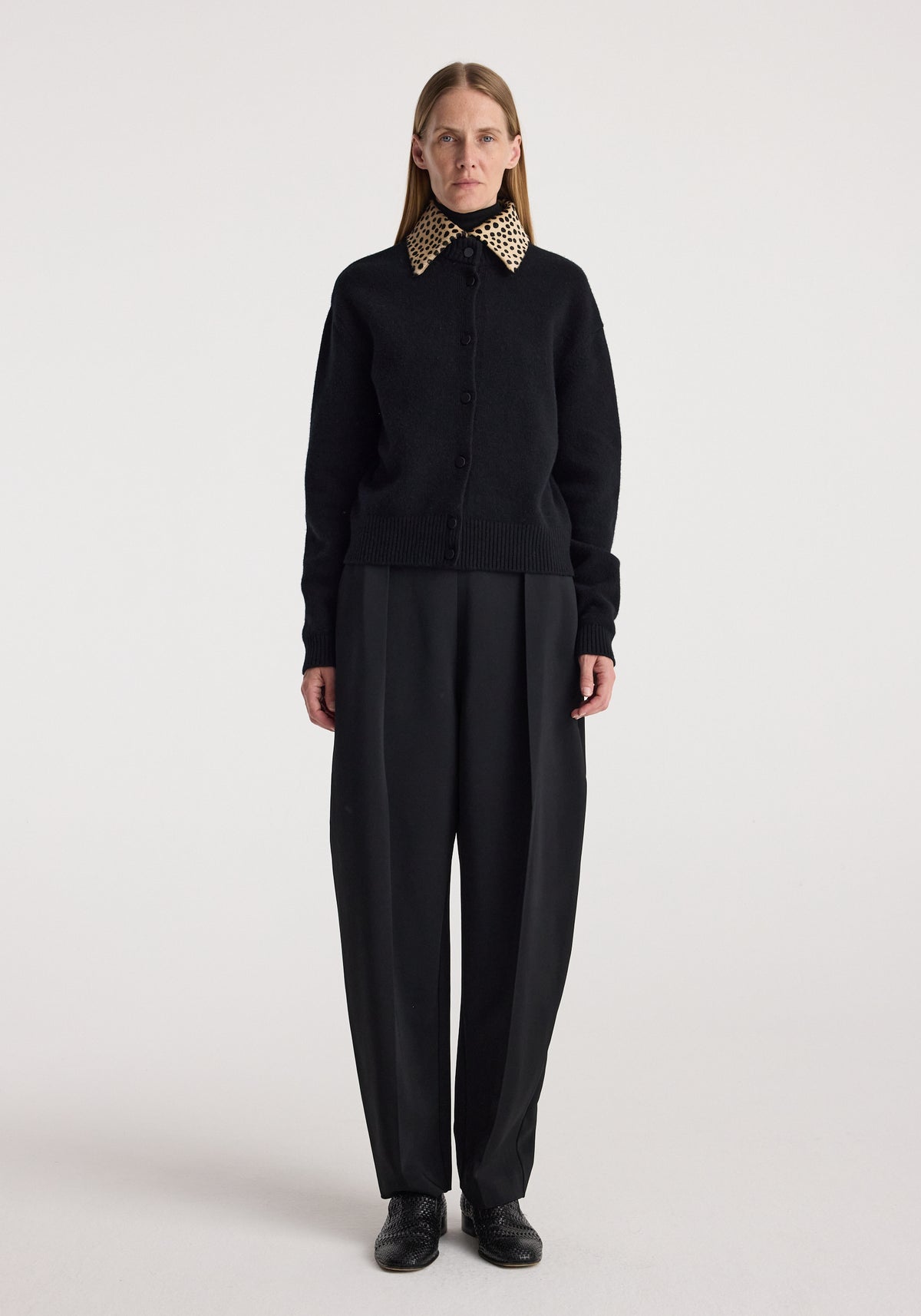 Woman wearing a black button-up sweater with a cheetah print collar, paired with loose black trousers and black shoes, modeling the Cheetah collar cardigan | black.